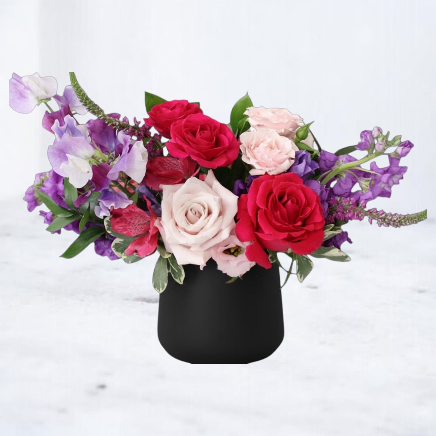 Mood Ring - Mood Ring is a bold, artful floral arrangement featuring rich red roses, lavender sweet peas, blush roses, deep purple stock, and seasonal textural blooms designed in a matte black vase. With its striking contrast of moody jewel tones and soft romantic hues, this arrangement feels modern, expressive, and effortlessly cool. Perfect for birthdays, celebrations, thank-you gifts, or anyone who loves statement florals with personality.  Designed with premium seasonal flowers and natural movement, Mood Ring brings a dramatic yet elevated feel to any space. Available for same-day flower delivery in Magnolia, The Woodlands, Montgomery, Conroe, Spring, Tomball, and surrounding Houston areas.