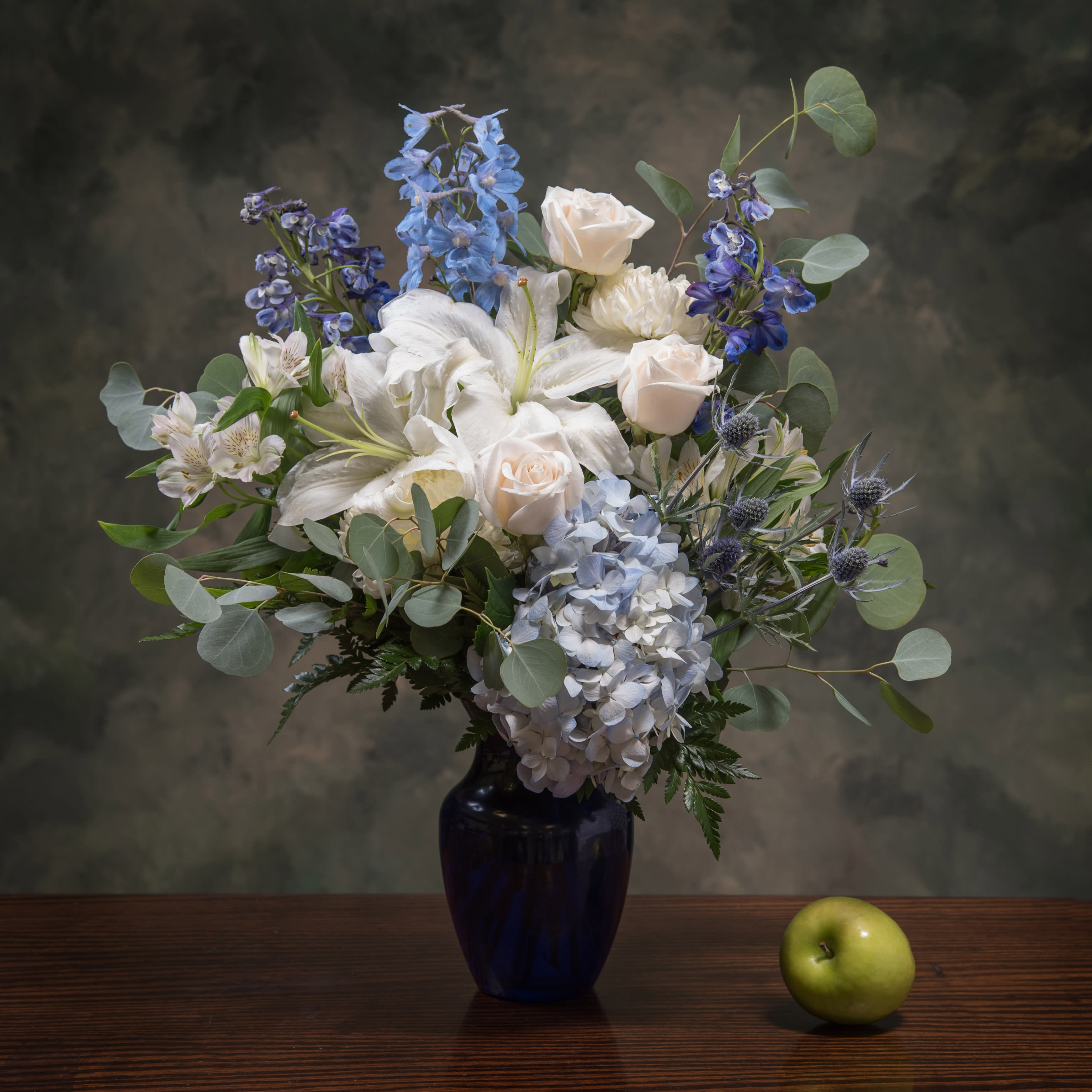 Bluetiful - This stunning mix of hydrangea, lilies and delphinium arranged in a cobalt blue vase is peaceful and elegant. Perfect to send to a gentleman or lover of blue, serene enough to send as an expression of sympathy too.