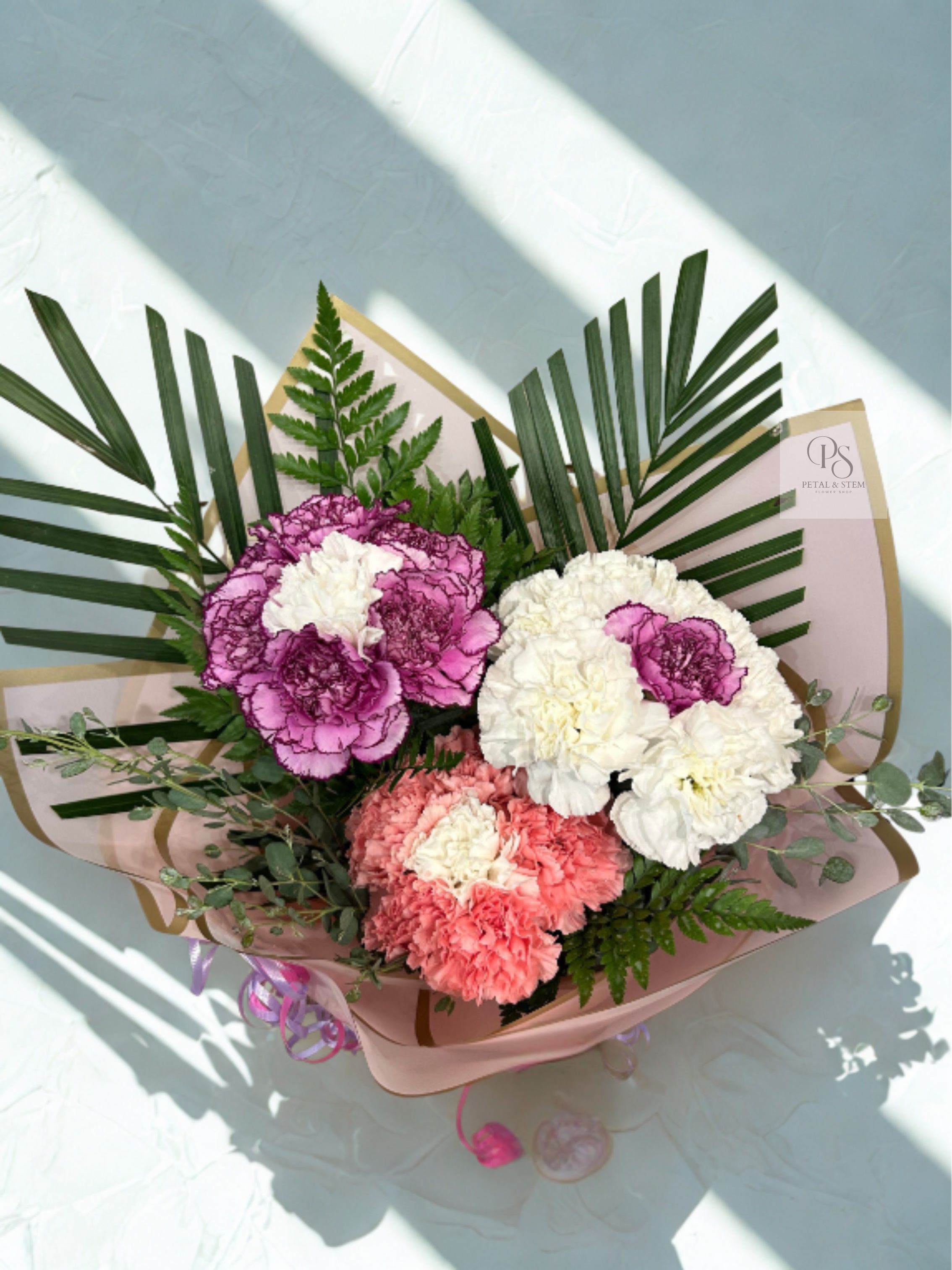 Bouquet of pink, white, and coral carnations with palm fronds