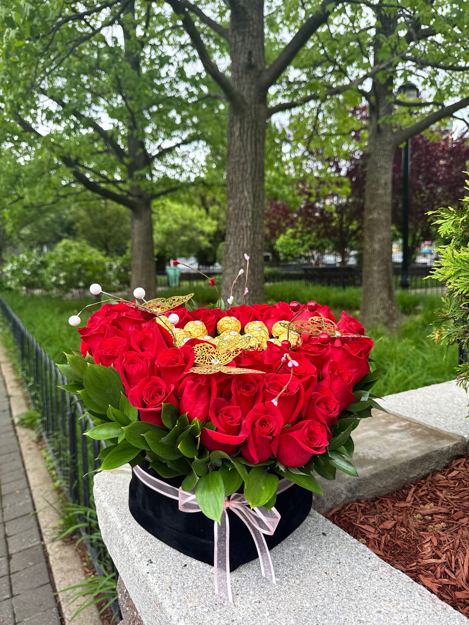 Heart-shaped box of red roses with gold chocolates and a pink ribbon