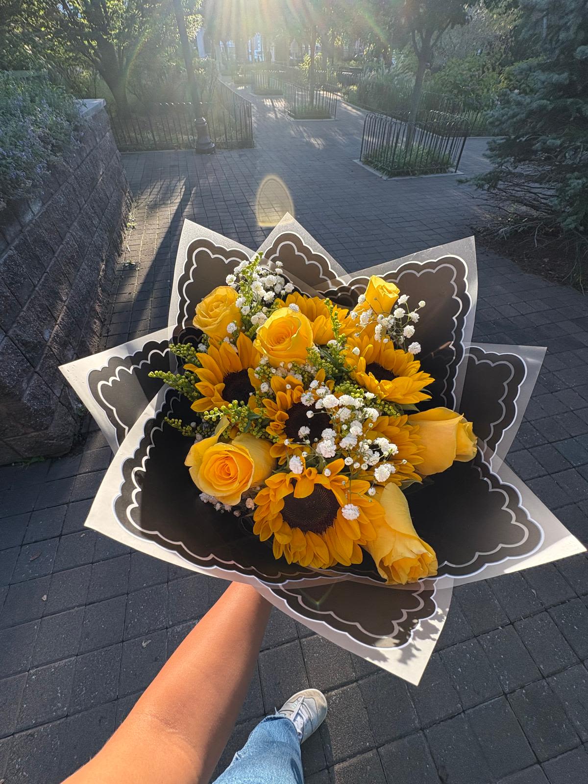 Handheld bouquet of yellow roses and sunflowers with white filler flowers