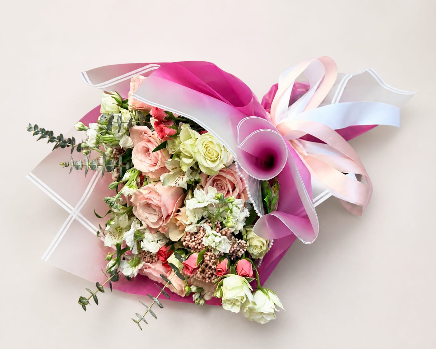 Moms Blush Elegance Hand Tied Bouquet  - Blush and cream roses mingle with soft pink spray roses and white alstroemeria in a hand-tied birthday bouquet that reads like a gentle embrace-perfect for Mother's Day, anniversaries, or a thoughtful thank-you. The mix of pastel blooms with brighter pink accents creates a romantic yet cheerful impression that will make the person you're thinking of feel truly celebrated.  This arrangement is hand-tied for a full, layered look and finished with decorative magenta wrapping paper and a pale satin ribbon for a polished, gift-ready presentation. Colors include pink, white, green, and peach, and the textured petals of roses paired with the delicate alstroemeria blossoms give visual depth and a soft fragrance that lingers. Ideal for sending warm wishes or marking a special moment, available in one carefully styled size-no assembly needed; simply place in fresh water on arrival to enjoy.