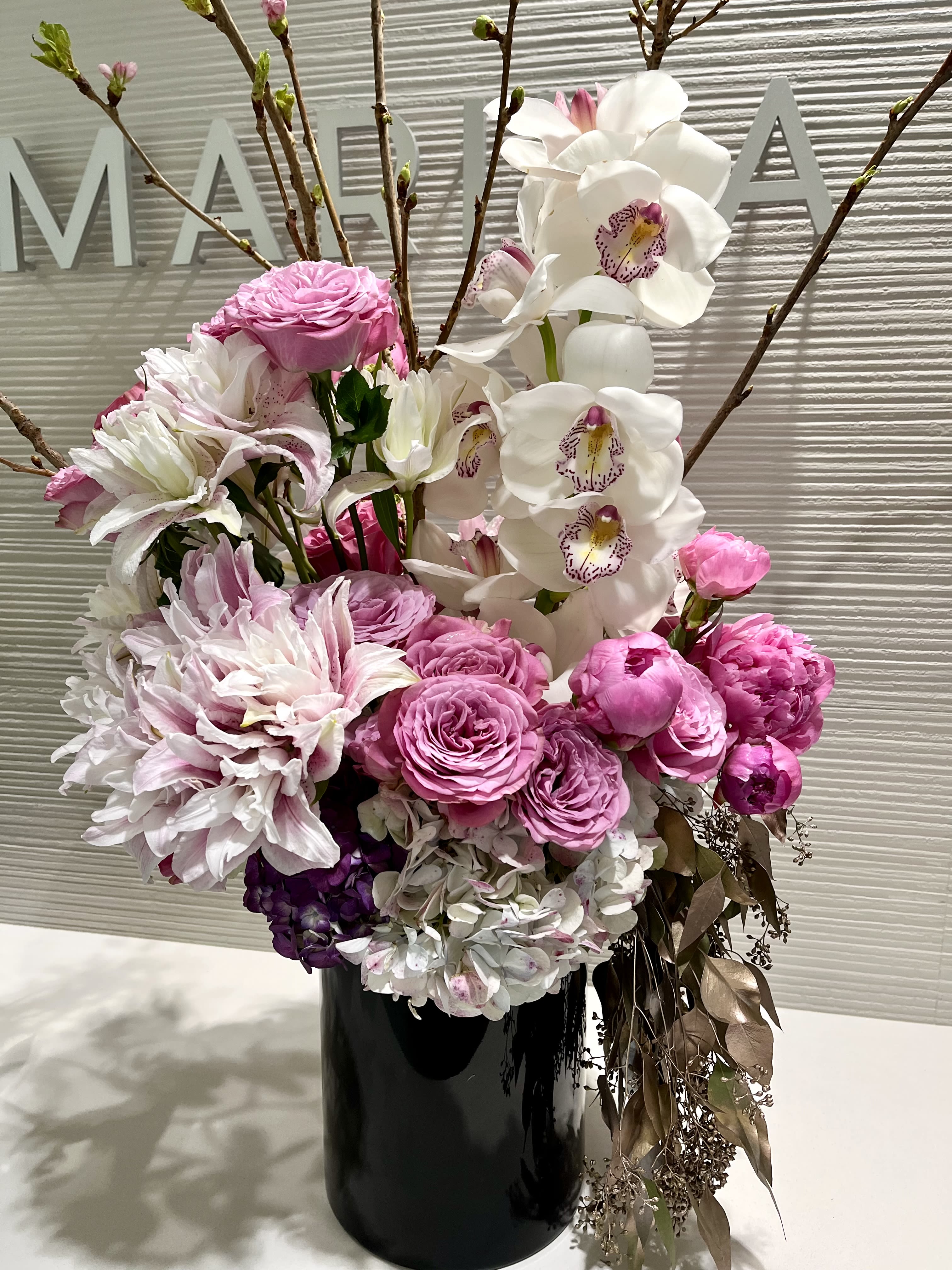Pink and white floral arrangement in a black vase