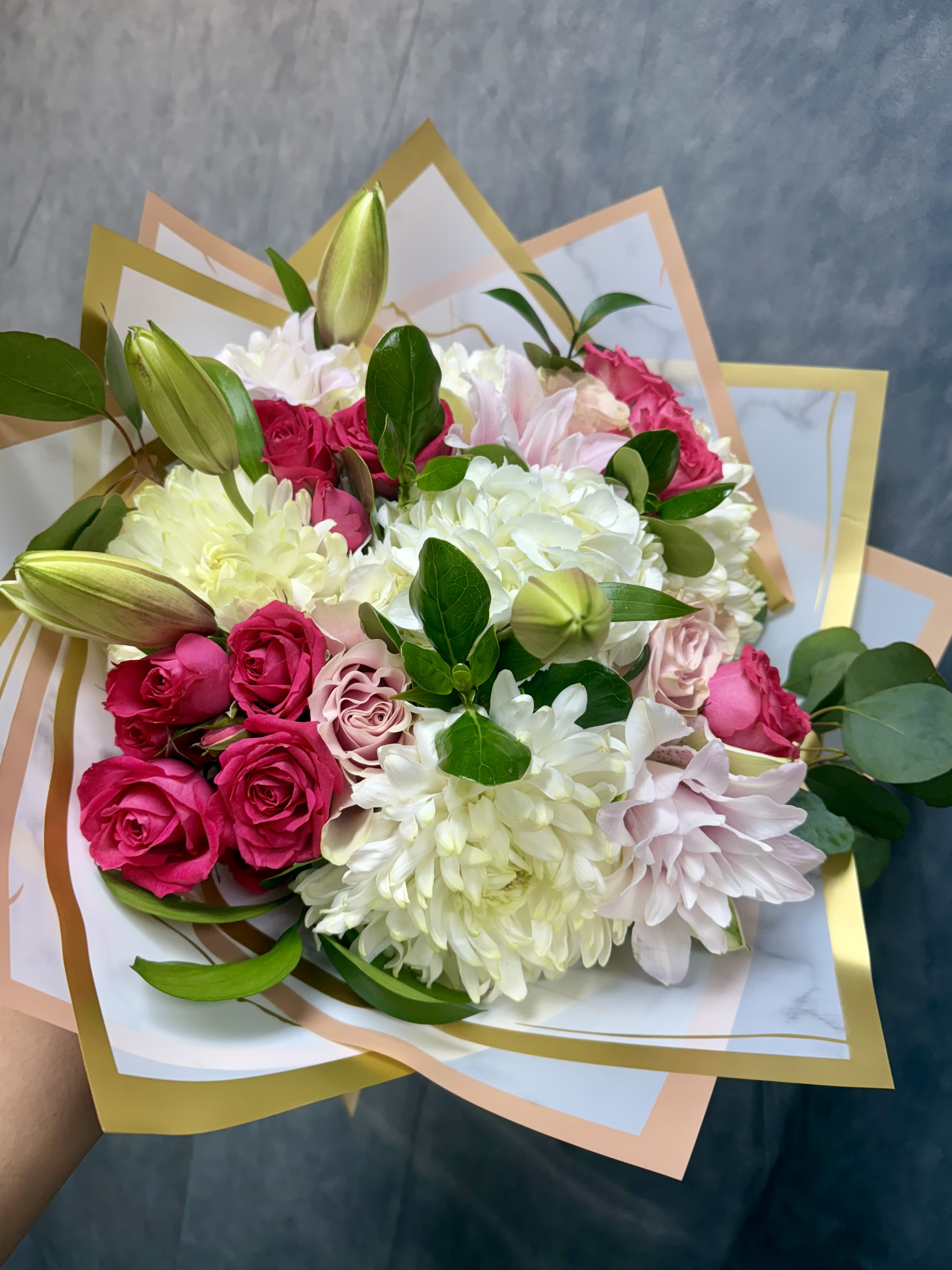 Bouquet of pink roses, white chrysanthemums, and lilies wrapped in pastel paper