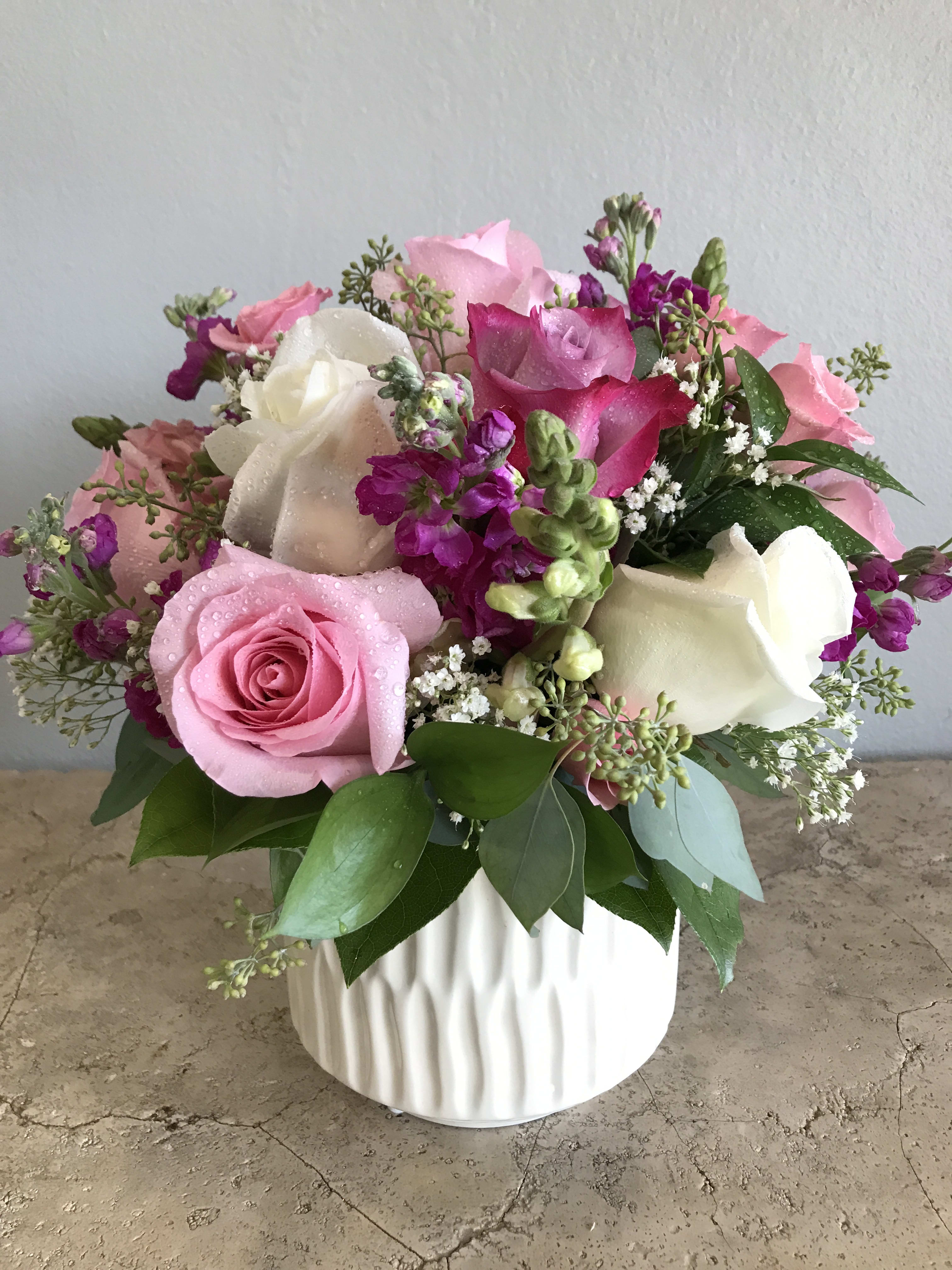 Pink and white roses arranged in a white vase.