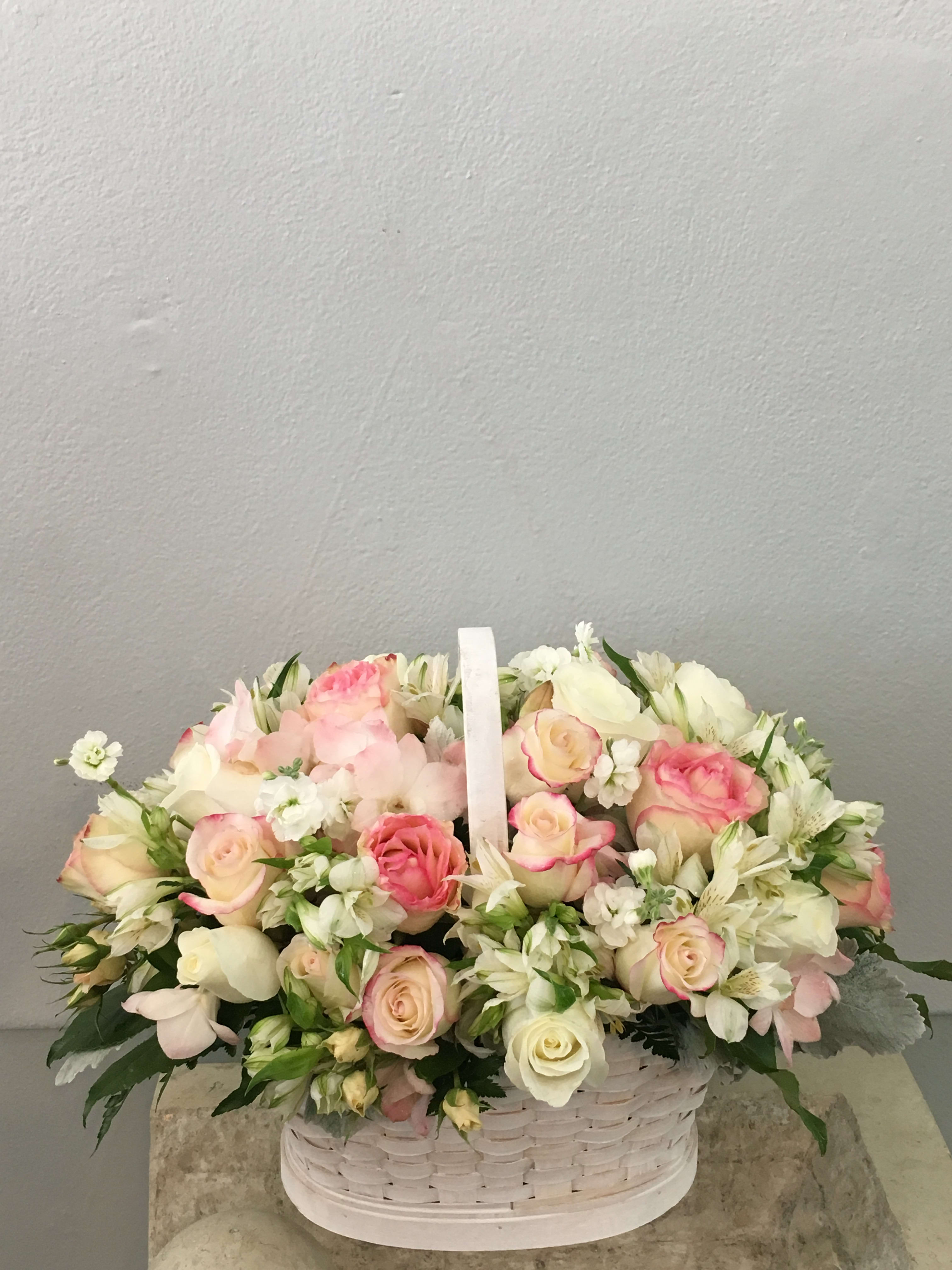 Basket of pink and white roses with small white flowers