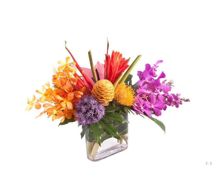 Colorful tropical flower arrangement in a clear rectangular vase