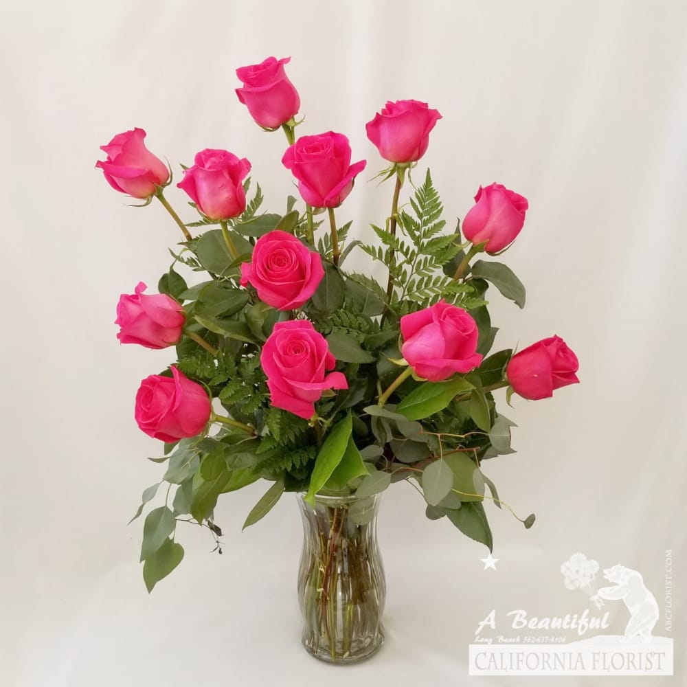 Beautiful Pink Roses Lush Accents In A Vase 3 Sizes Available - Beautiful arrangement of long stem PINK roses arranged in a vase and accented by lush greens. Shade of Pink may vary depending on stock on hand.  ***CHOOSE NUMBER OF ROSES*** as follows:  STANDARD - One dozen (12) gorgeous (pictured)  PREMIUM - Two Dozen (24) gorgeous roses 
