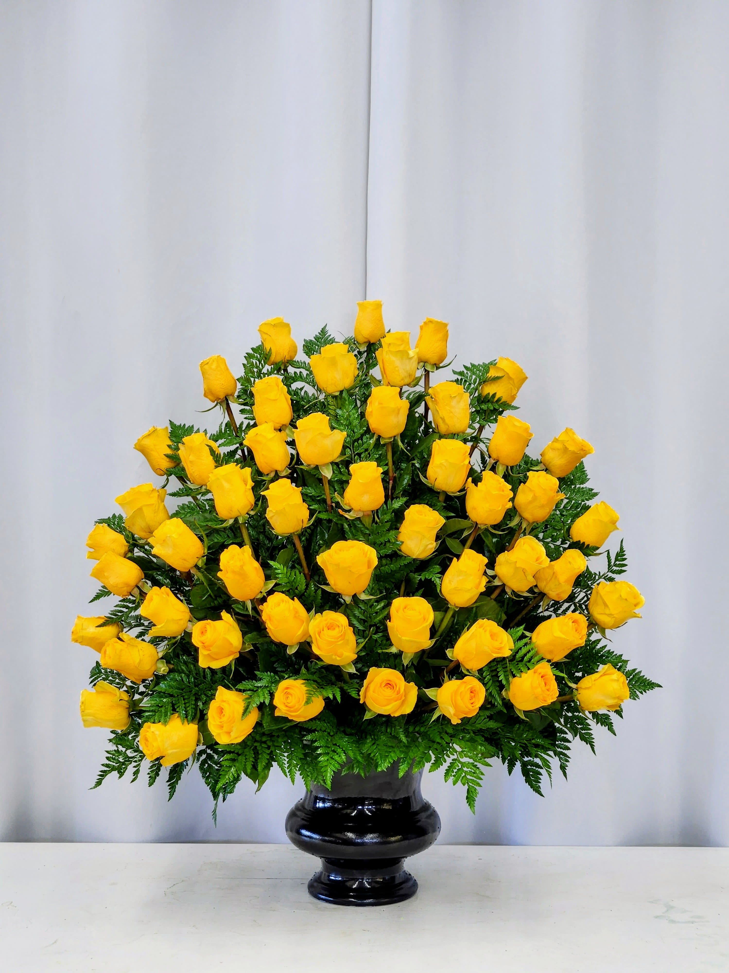 Cheerful Celebration - A glowing cluster of bright yellow roses creates immediate warmth-perfect as a Event Flowers or Sympathy to a home or Church. The full-bodied design is elegant and luxurious.  The glossy black vase adds a formal, grounding contrast that makes the yellow pop and suits both celebratory and more reserved occasions like sympathy.  CALL US FOR ANY SPECIAL REQUEST OR CHANGE OF COLOR. 562-437-4106. A beautiful California Florist is here to serve you!  