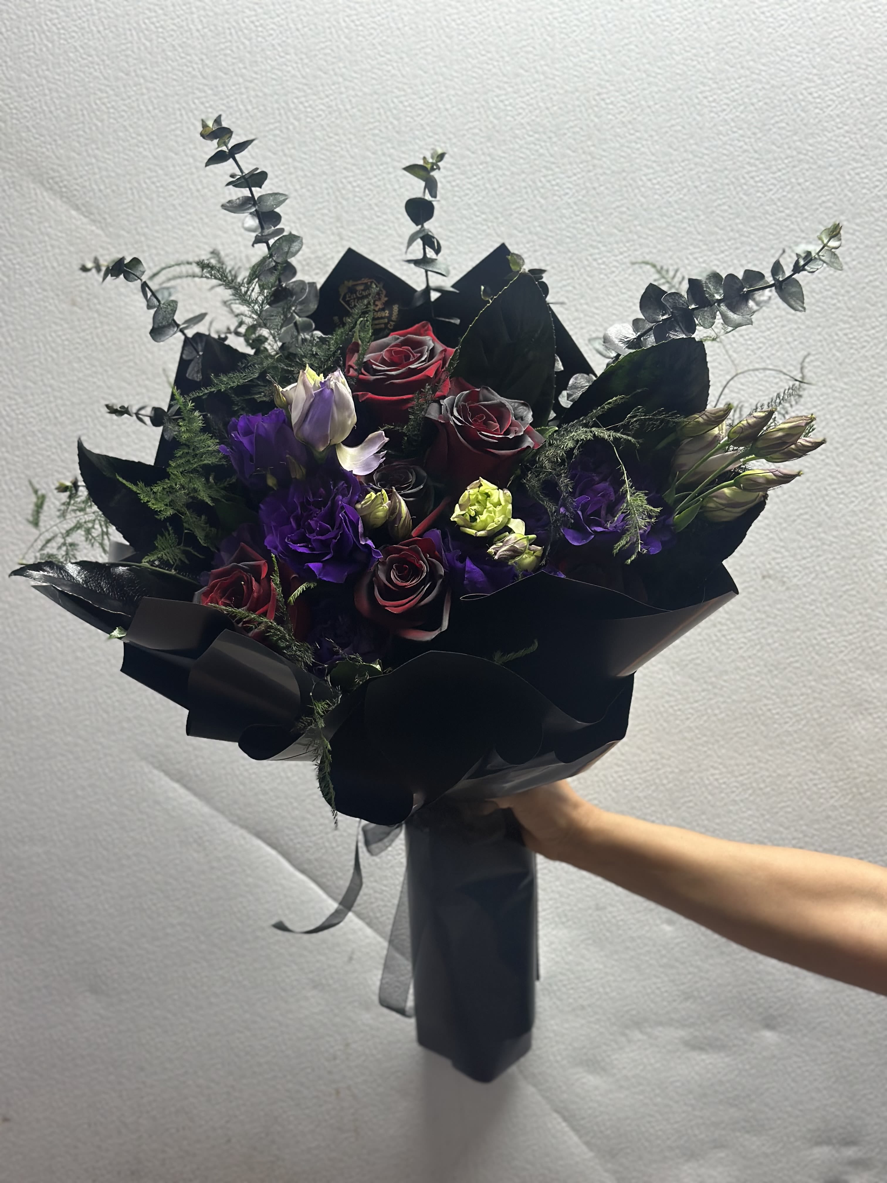 Bouquet of dark red roses and purple lisianthus with black wrapping