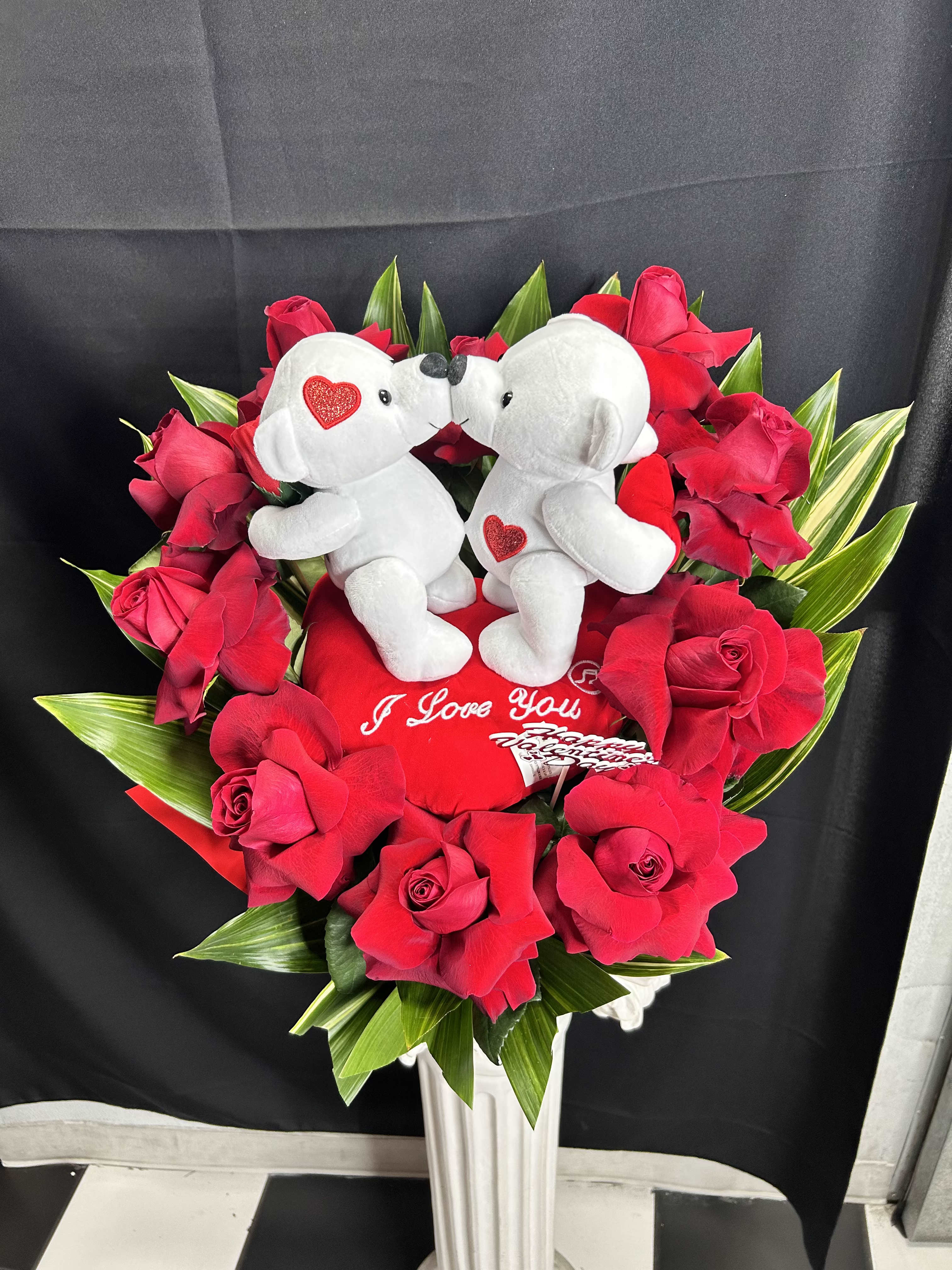 Red rose arrangement with two white teddy bears and a heart pillow