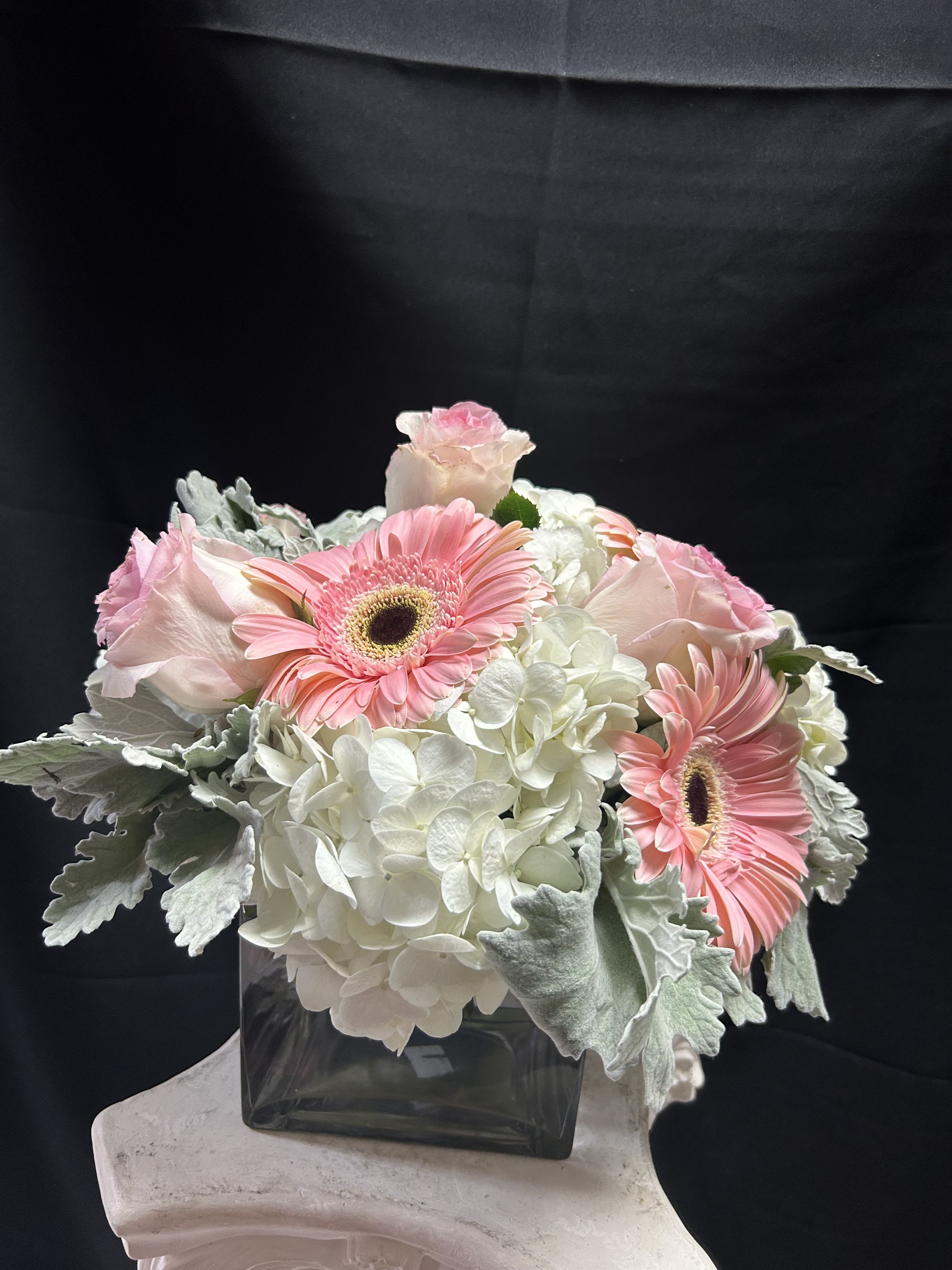 Pink gerbera daisies and pale roses in a square glass vase