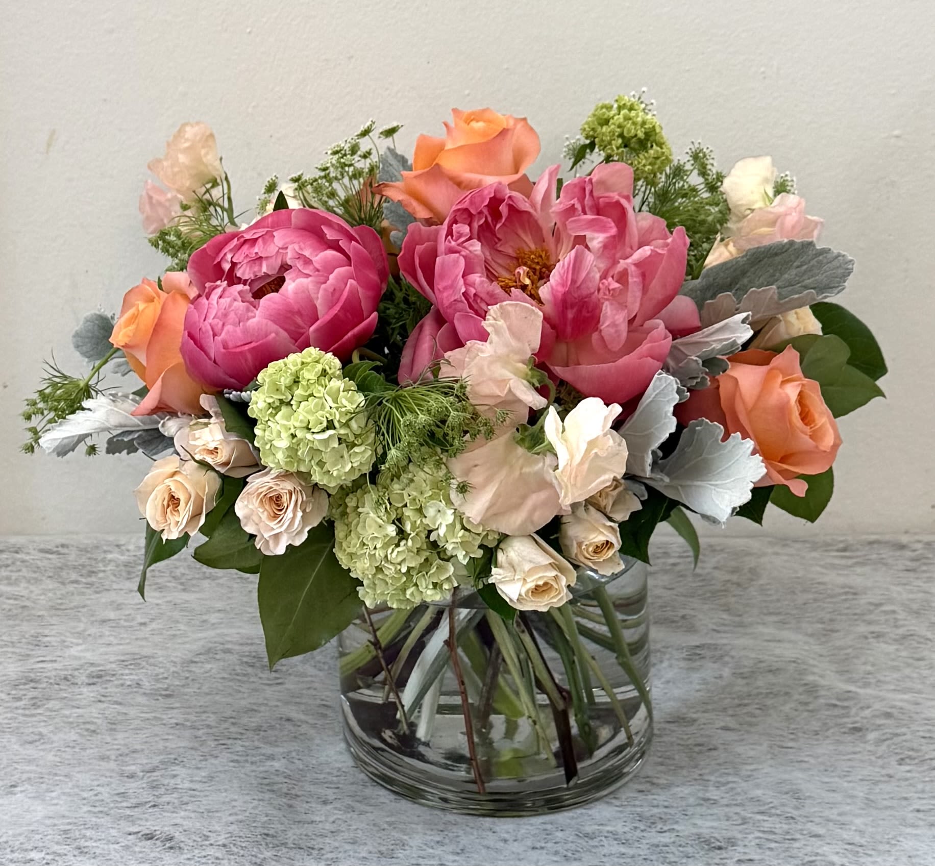 Mixed pink and peach flower arrangement in a clear glass vase