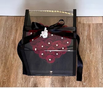 Black gift box with red rose design and a black ribbon bow
