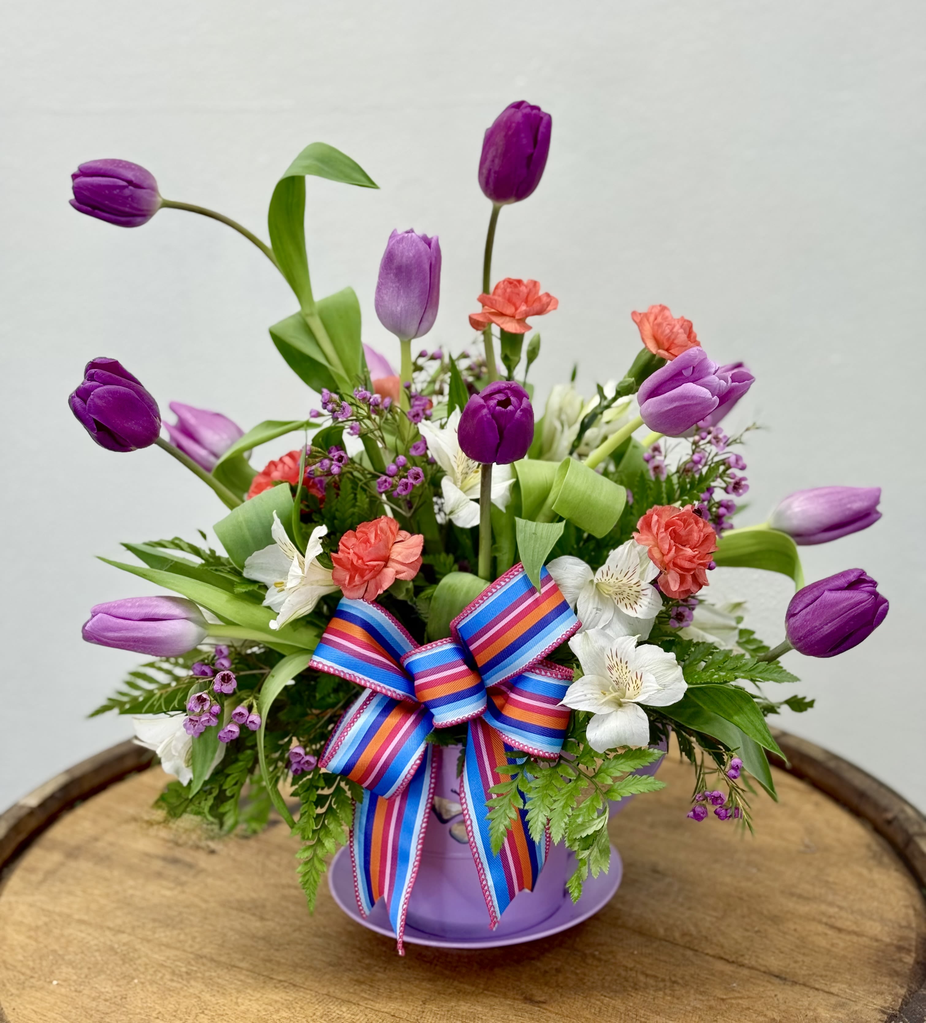 Tea &amp; Tulips - Tall purple tulips with white alstroemeria, coral-pink carnations in a lavender teacup planter. Other color options could include green, pink, and teal for the teacup. Limited availability on tulip colors. We will for Mother's Day be mixing tulips 