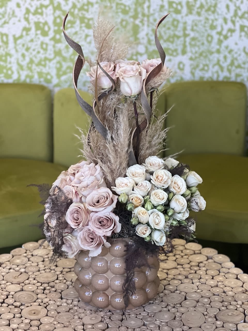Pink and white rose arrangement in a textured vase with dried grasses