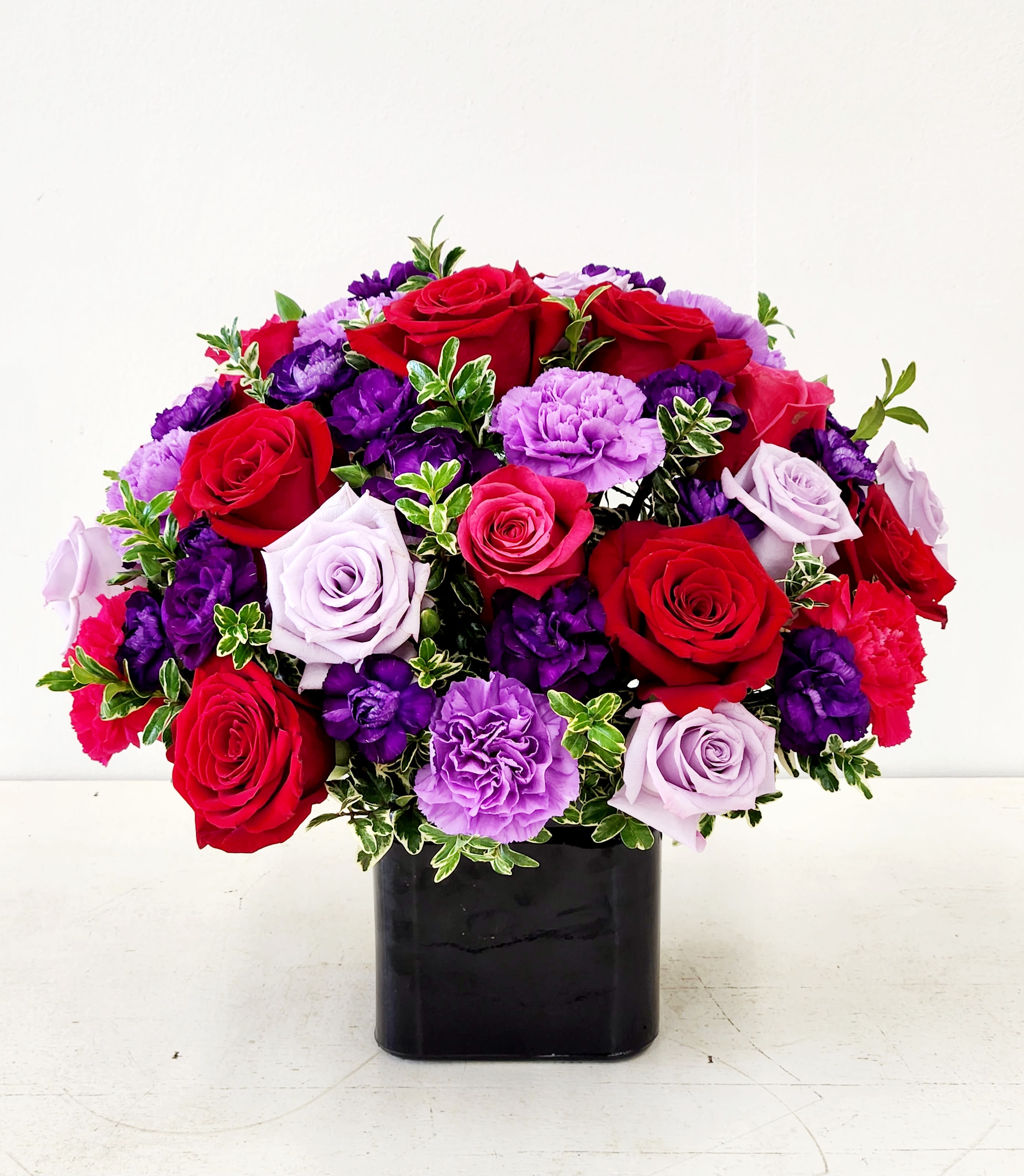 My Love, My Gem - A rich, romantic cluster of red, purple, pink and white roses makes a bold first impression-My Love, My Gem is a flower arrangement designed for anniversaries, Valentine's Day, or any moment you want the person you're thinking of to feel cherished. The deep reds and regal purples read as passionate and refined, while the softer pinks and touches of white lend a tender, celebratory warmth.  Say I love you with this beautiful and unique design. 