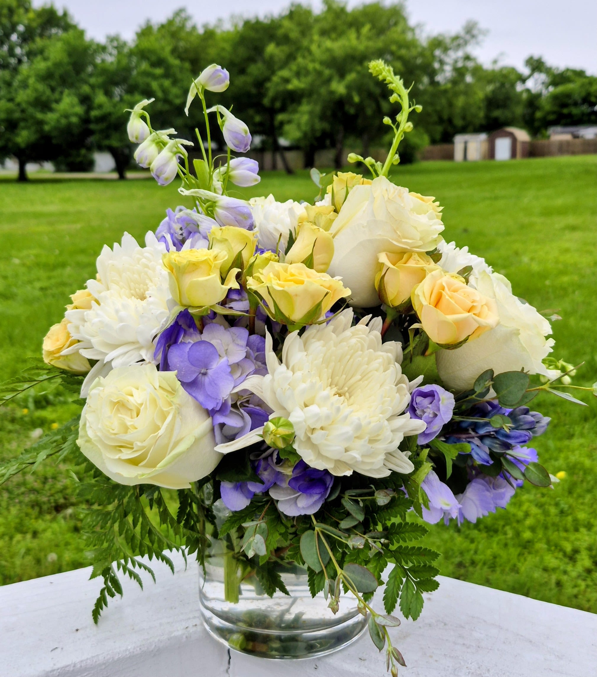 Lavender Meadow Elegance - Arranged in a clear glass vase, this piece captures the perfect balance of elegance and charm—ideal for birthdays, sympathy, thinking-of-you moments, or simply brightening someone’s day. The soft color palette makes it a versatile favorite that feels both comforting and refined.