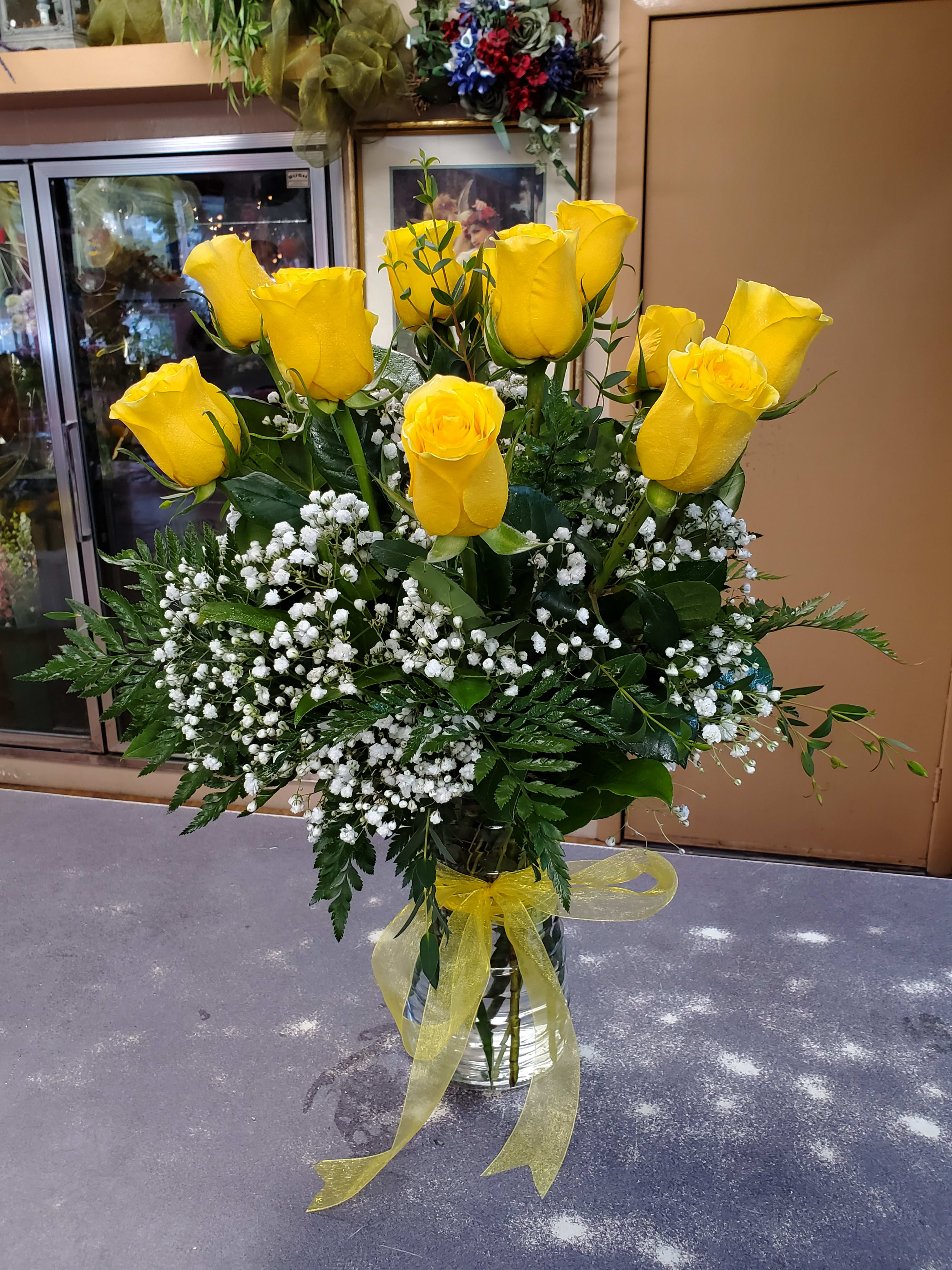 Bouquet of yellow roses with white baby's breath in a glass vase