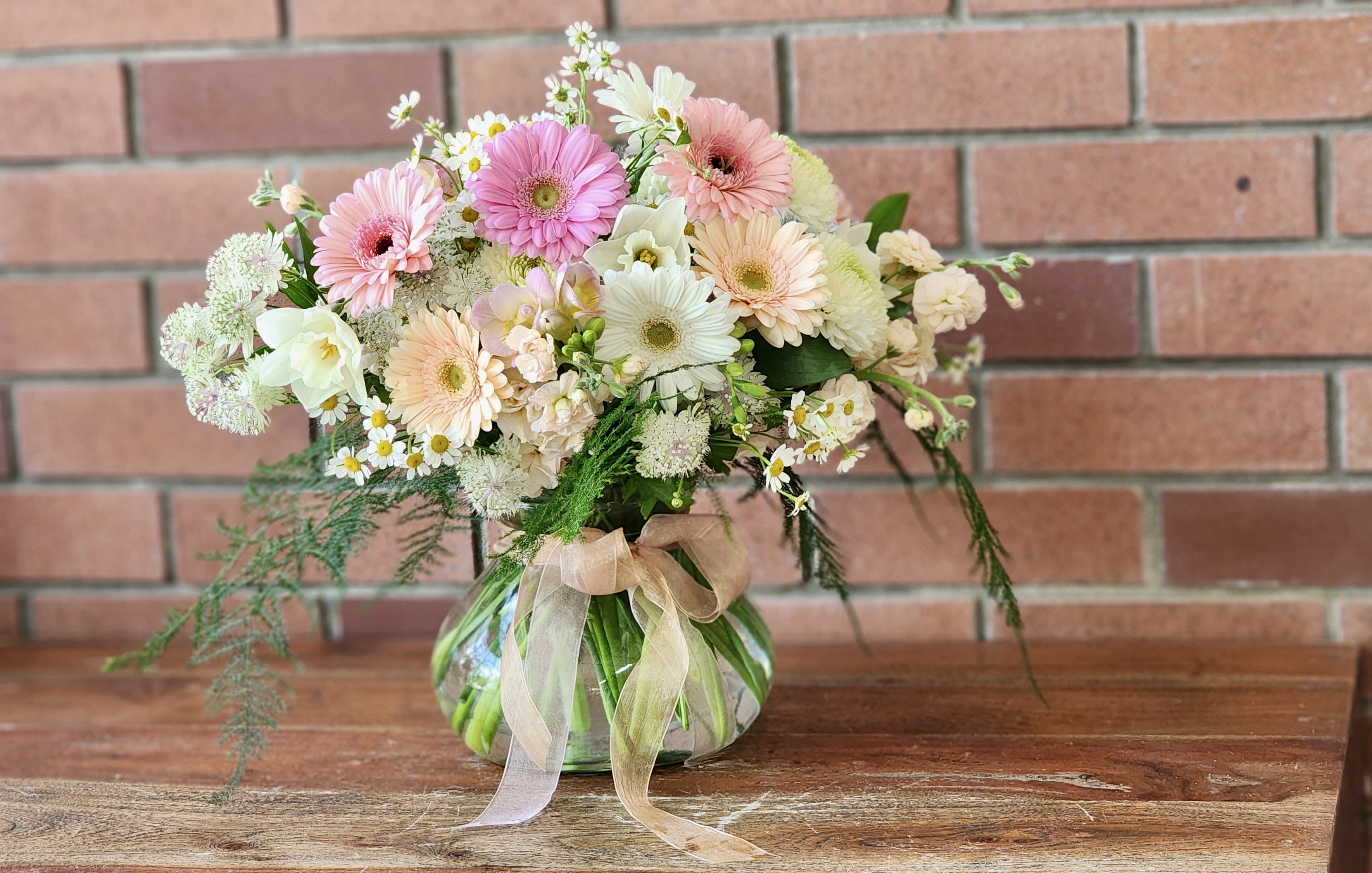 Pastel mixed bouquet in a round glass vase with a ribbon