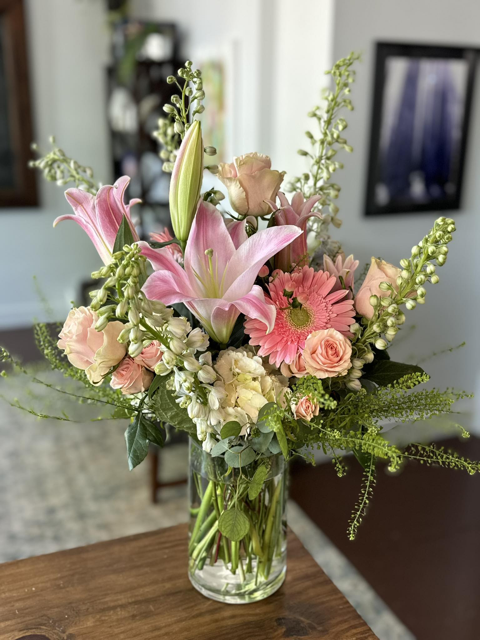 Made of Magic (M.O.M) - Soft pink lilies open like warm smiles in this garden-style bouquet, a Mother's Day-ready flower arrangement that also fits birthdays, anniversaries, thank-you moments, or simply "just because." The mix of peach and blush roses with a single bright pink gerbera daisy creates a gently romantic yet cheerful impression-she'll feel seen and celebrated the moment the vase arrives.  Perfect for the person who appreciates refined, feminine blooms without being overly formal, this arrangement brightens a breakfast table, desk, or mantel. Vase-arranged and ready to display, it arrives with simple care: fresh water and a cool spot will keep the flowers looking their best for days-an easy, meaningful way to say "thank you," "happy birthday," or "I love you."