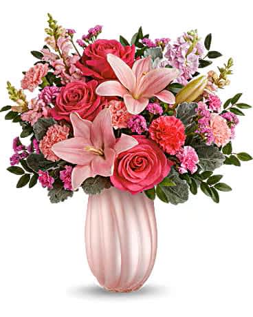 Rosy Swirls Bouquet - Create magic for Mom with our pearlescent glass vase, complimented by a bouquet of hot pink roses, pink asiatic lilies, light pink and hot pink carnations, miniature carnations, pink snapdragon, light pink stock, statice and nice greenery, a Mother's Day surprise she'll cherish. 19"h x 18"w a one-sided arrangement