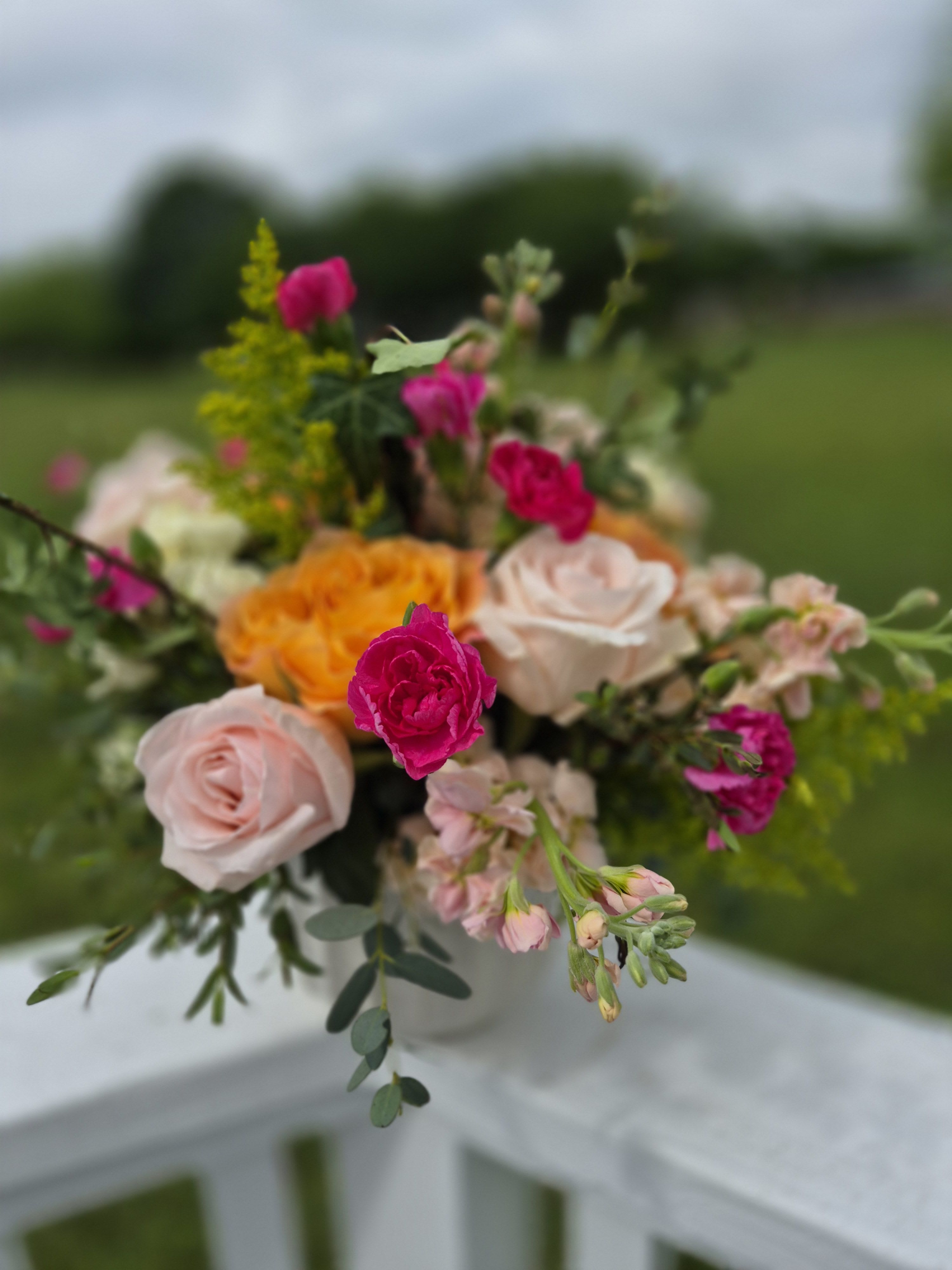 Sunset Garden Charm - This arrangement is artfully designed in a modern white vessel. Airy greenery adds and a fresh-from-the-garden feel, making it perfect for birthdays, celebrations, or simply brightening someone’s day.