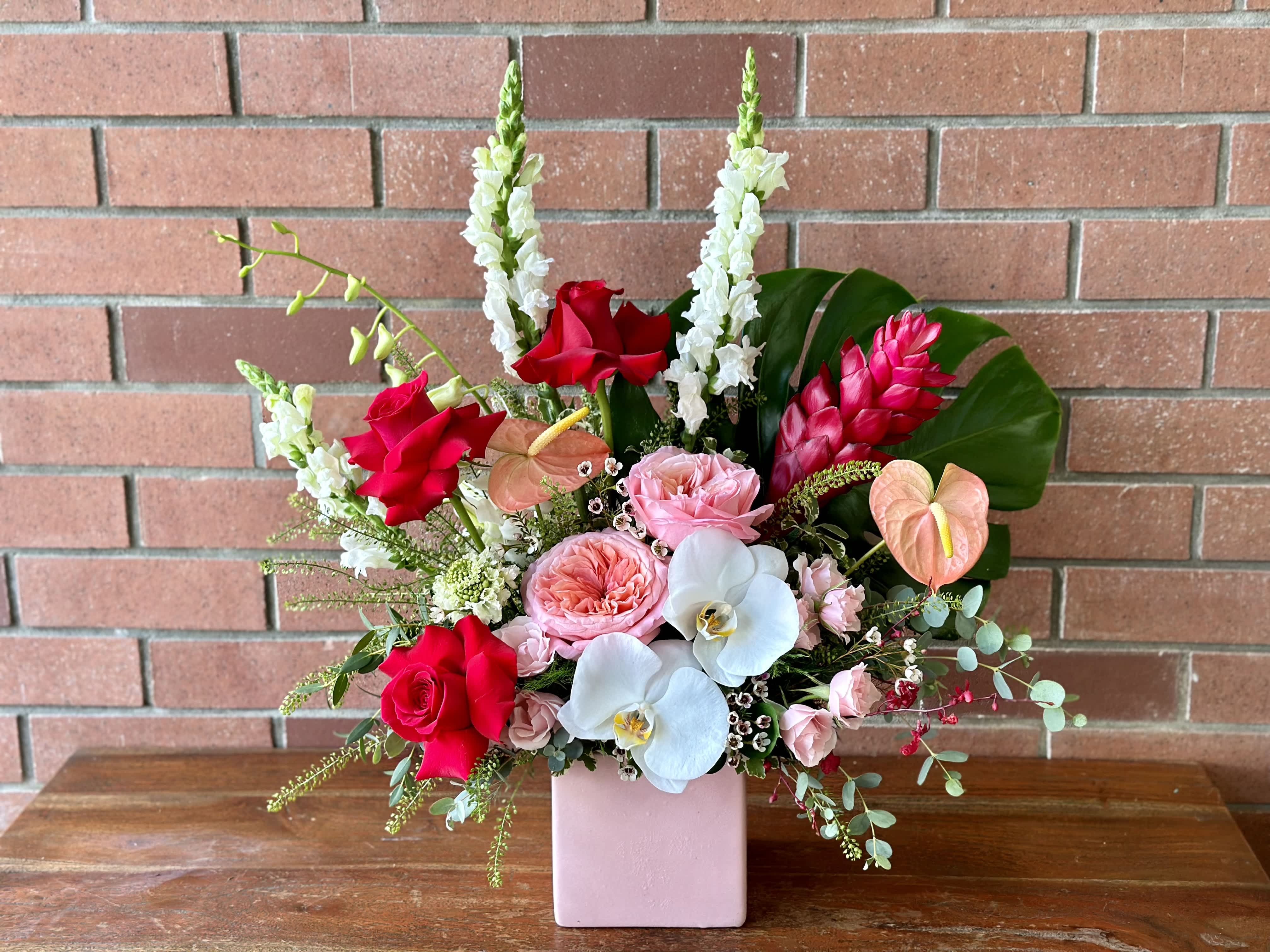 Mixed bouquet in a pink vase with red, pink, white, and peach flowers