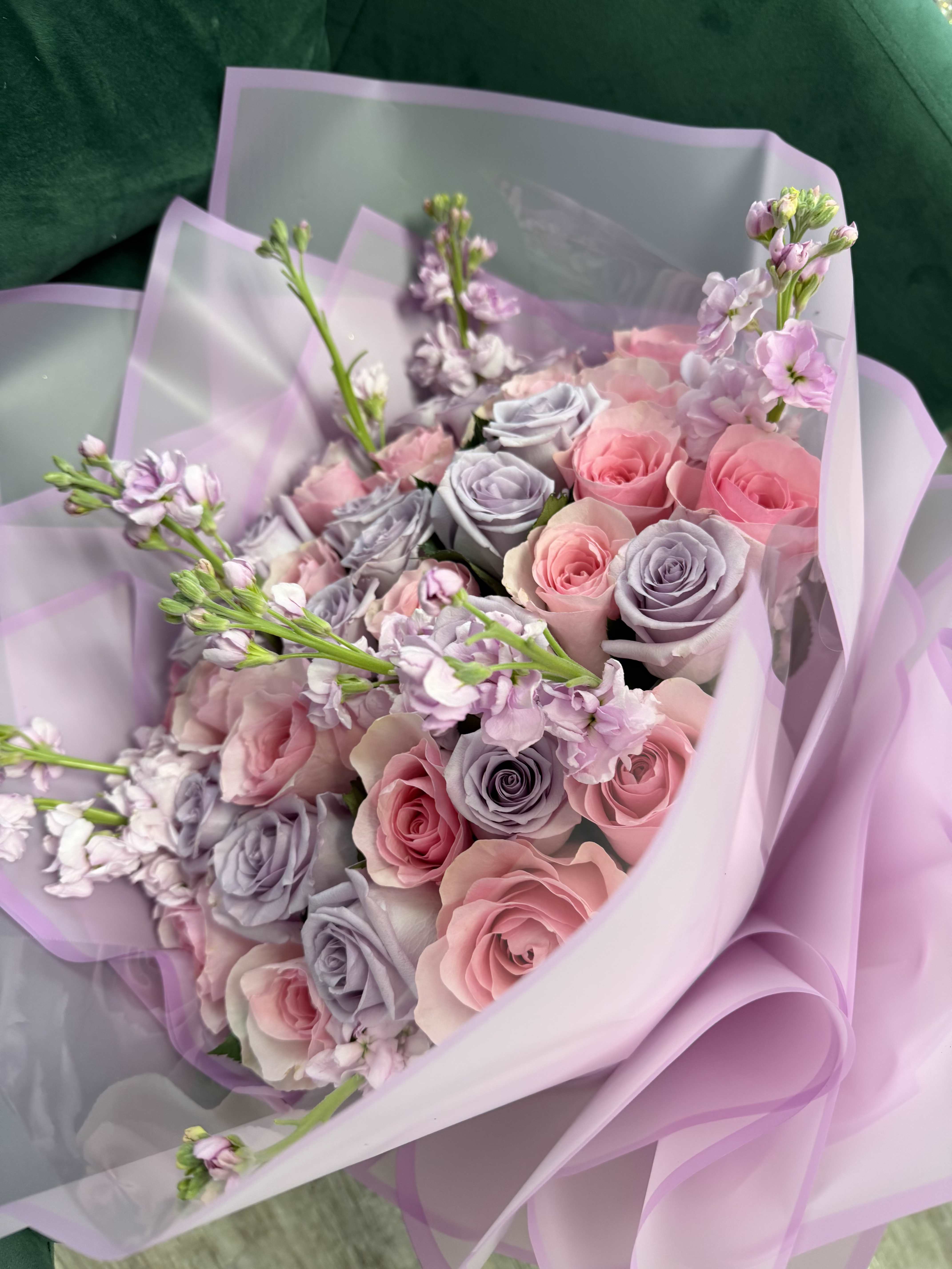 The Lavender Haze Dream - Step into a world of soft colors and sweet scents with our Lavender Haze Dream bouquet. This expertly curated arrangement features a lush blend of premium cool-toned lavender roses and delicate blush pink roses, creating a seamless gradient of pastel perfection.  To add height and a touch of fragrance, we’ve integrated fresh purple stock flowers, known for their spicy-sweet aroma and ruffled texture. The bouquet is presented in our signature frosted violet waterproof wrap, which enhances the blooms' soft glow while offering a sleek, contemporary silhouette. It’s a chic choice for anyone who loves modern aesthetics and romantic florals.