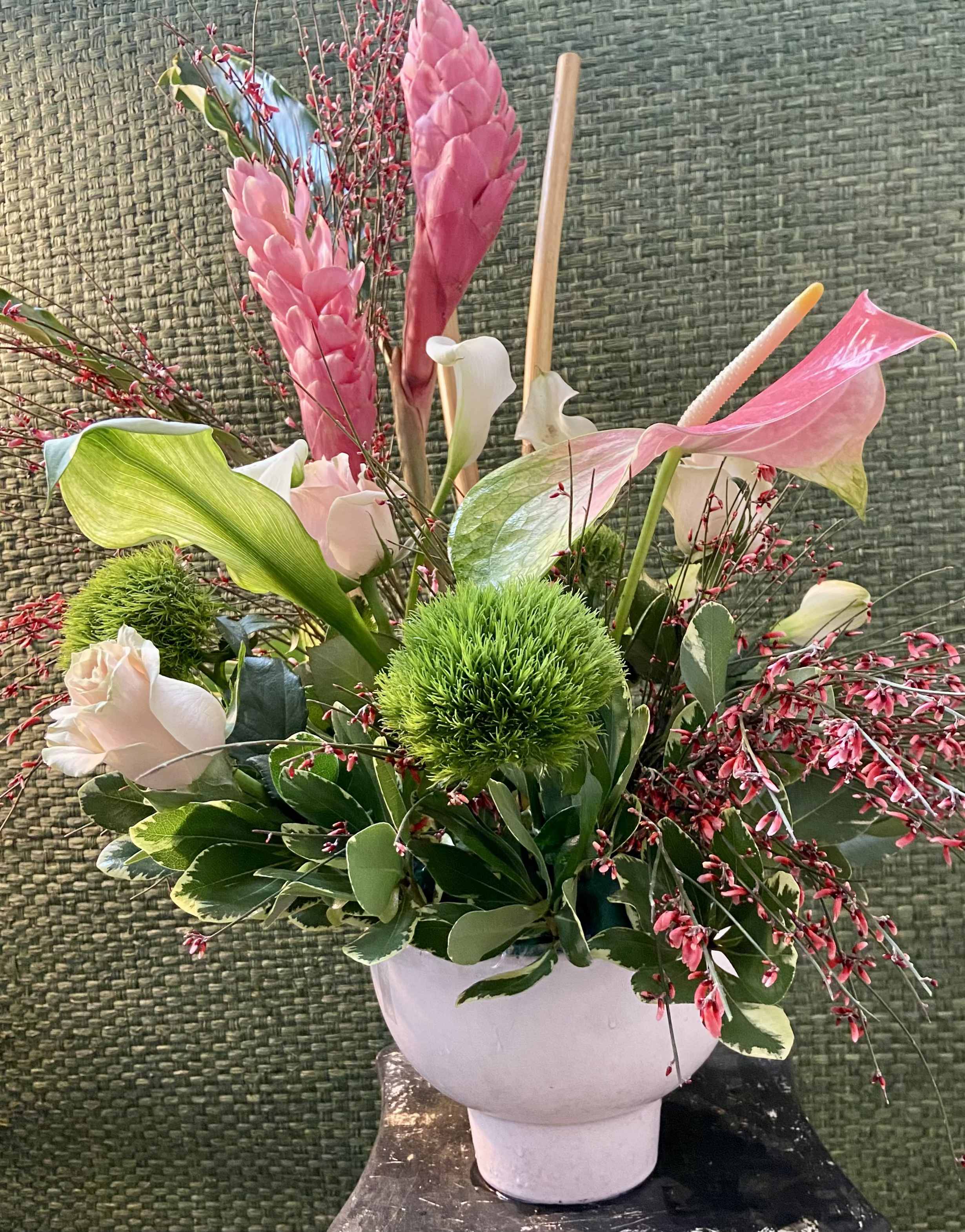 One of a Kind - A Unique Mother's Day Special with a tropical flair designed in a frosty pink compote container.  Pink ginger, pink and green anthurium, green dianthus, pink Leptospermum, pink mondial roses, a ginger leaf and bamboo to finish off this special piece. Sure to please the Mom who loves the tropical blooms. 