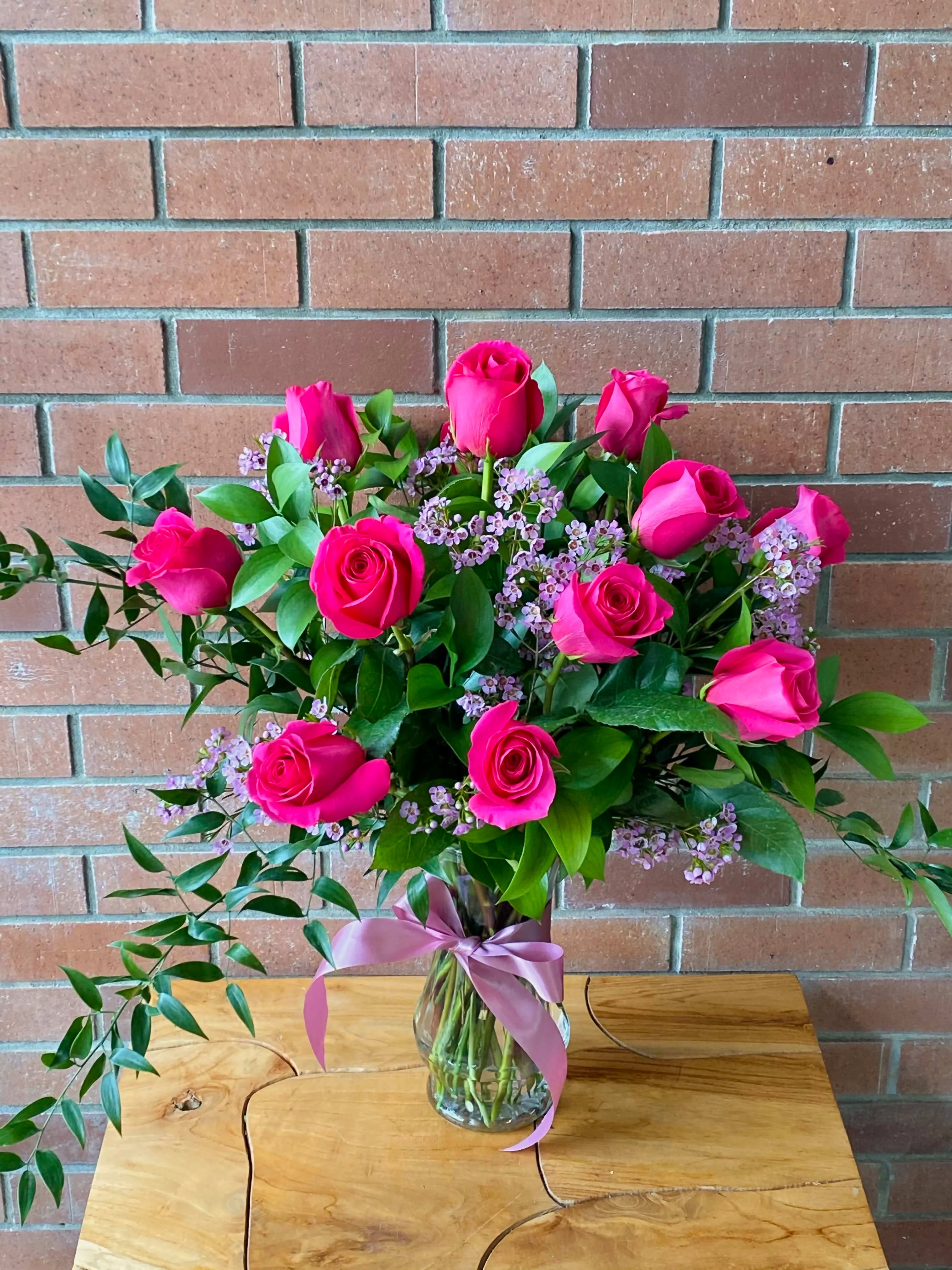 Pink roses arranged in a glass vase with a ribbon