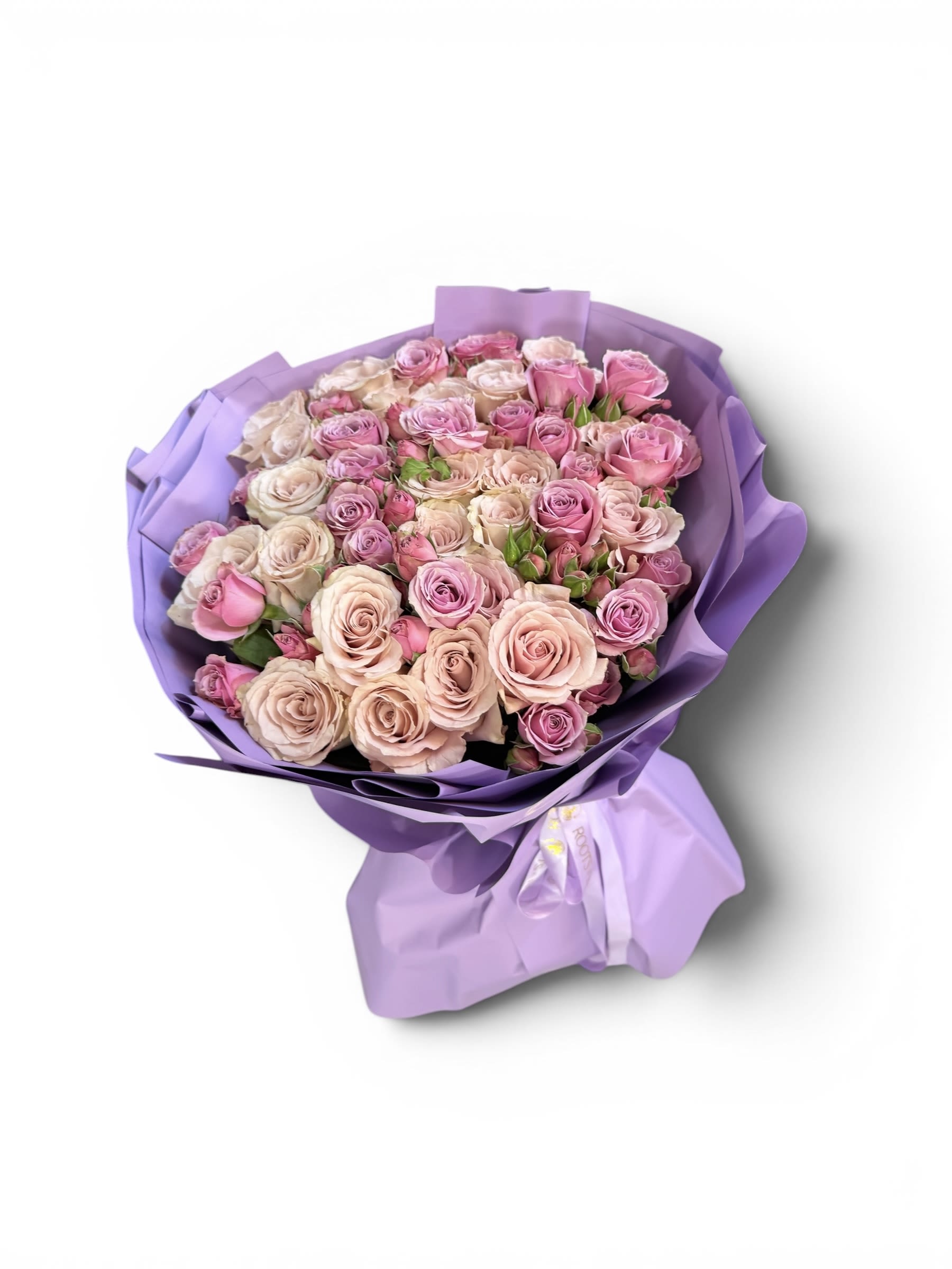 Rose Velvet Bouquet  - A lush hand-tied bouquet featuring an elegant blend of blush, soft pink, and creamy nude roses, wrapped in a statement lavender presentation. 