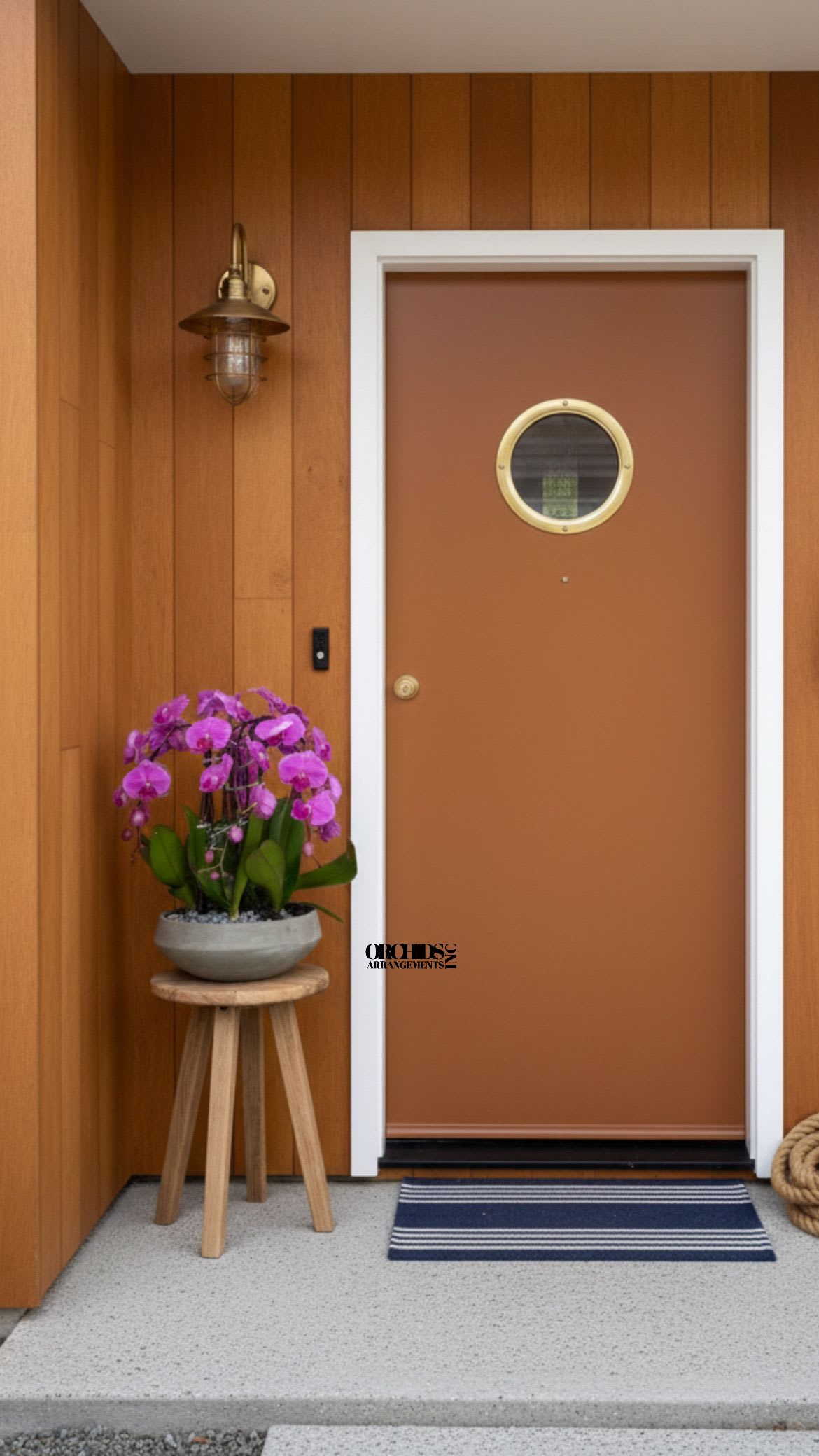 Potted purple orchids on a small wooden stool beside a front door