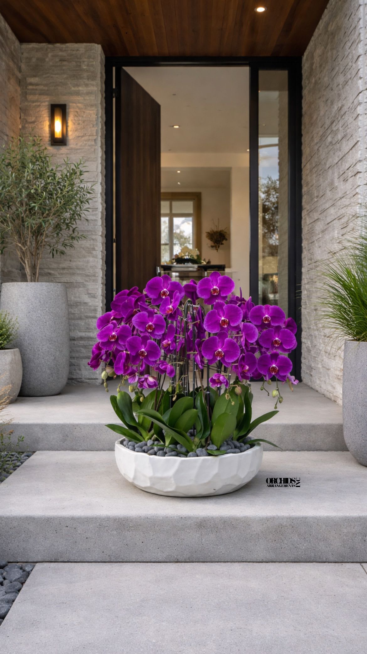 Low white bowl of vivid purple orchids on modern concrete entry steps
