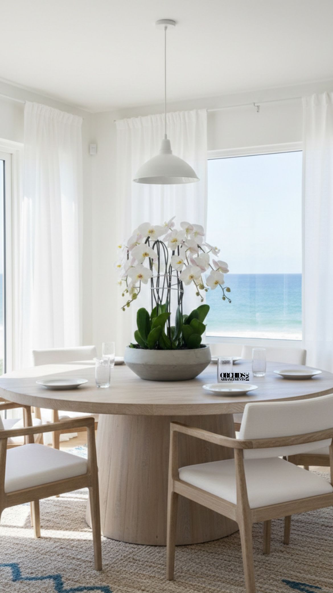 White orchids in a low bowl centerpiece on a dining table