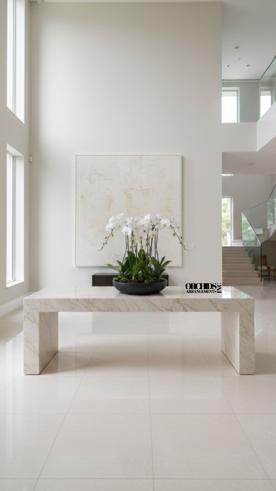 White orchid arrangement in a black bowl on a marble table