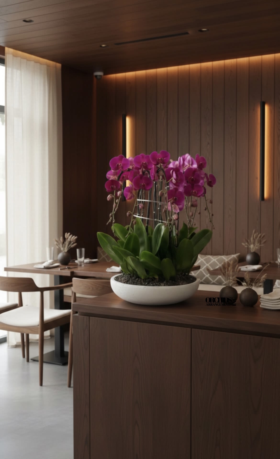 Pink orchids in a white bowl planter on a wooden table
