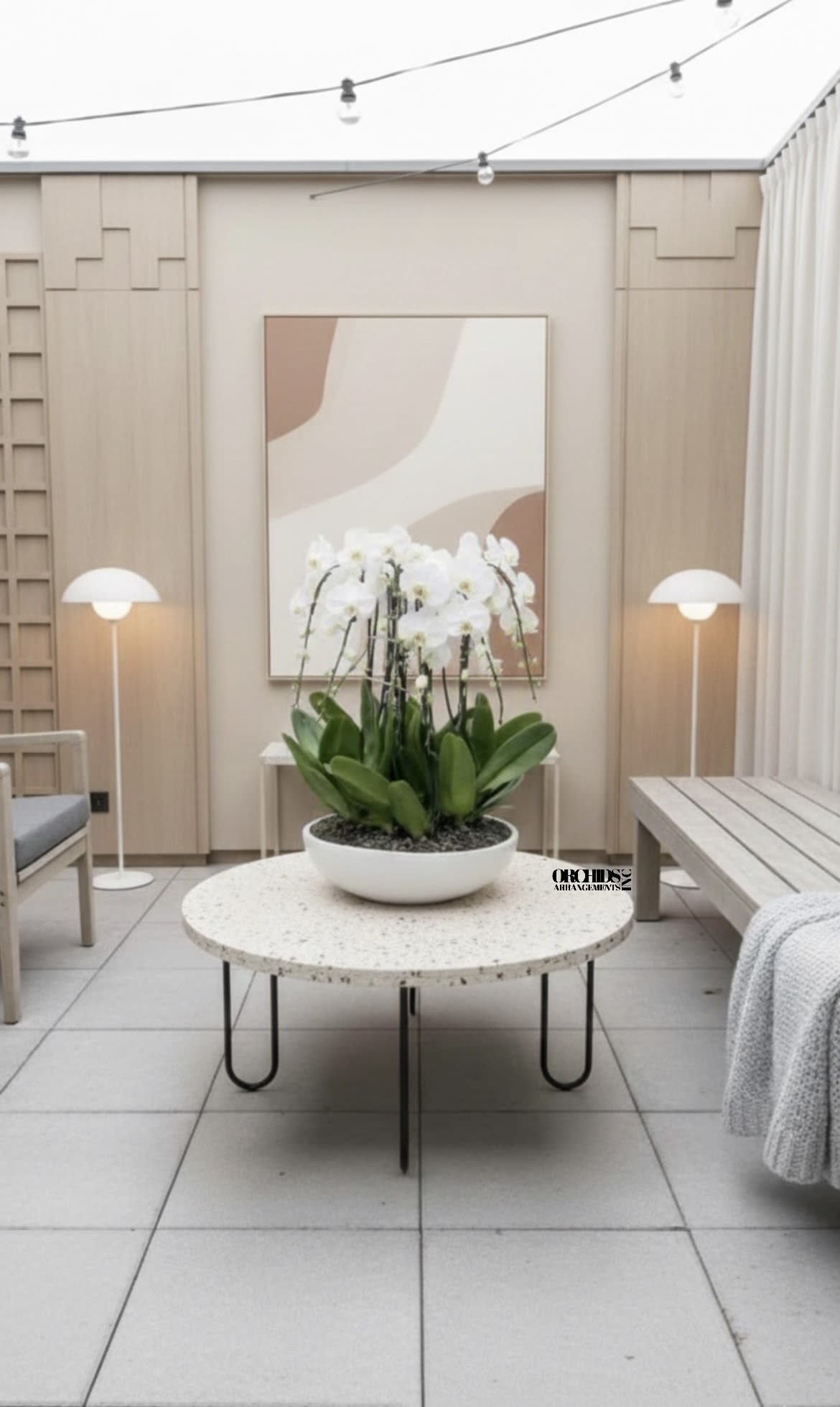 White orchid arrangement in a shallow white bowl on a table