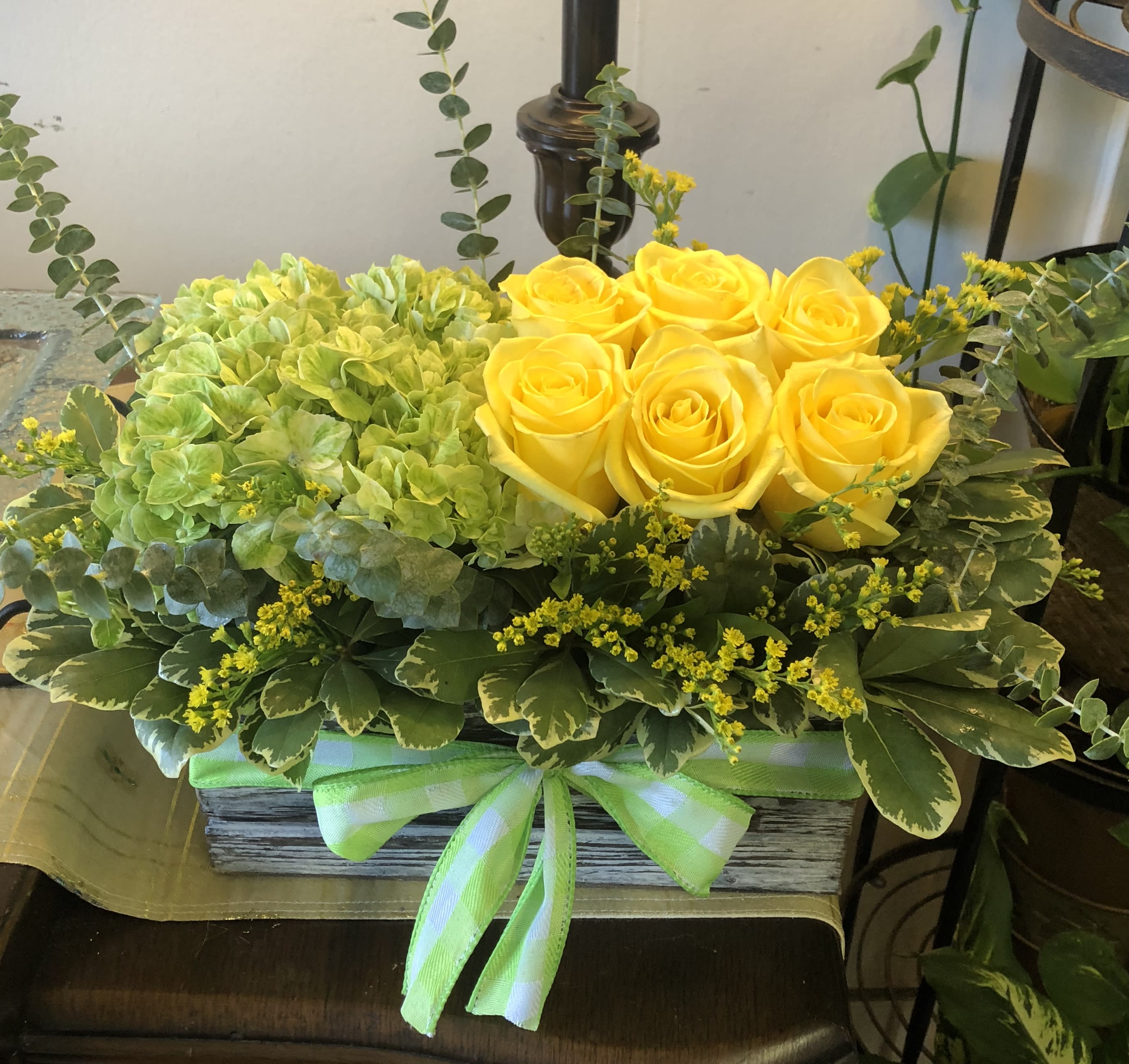 Yellow roses and green hydrangeas in a rectangular box with a ribbon