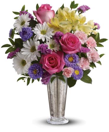 Mixed bouquet of pink roses, daisies, and lilies in a silver vase