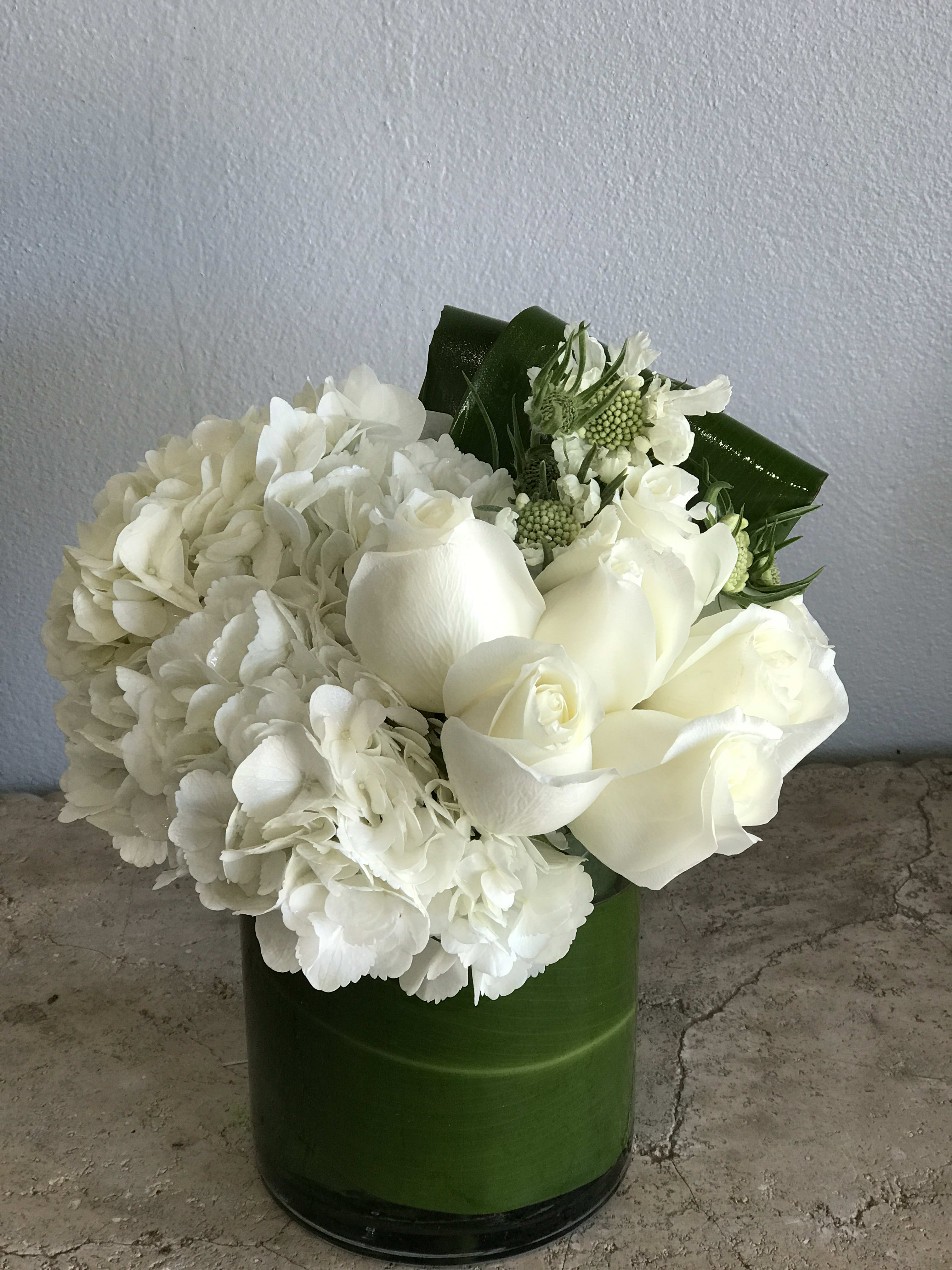 White roses and hydrangeas arranged in a green vase