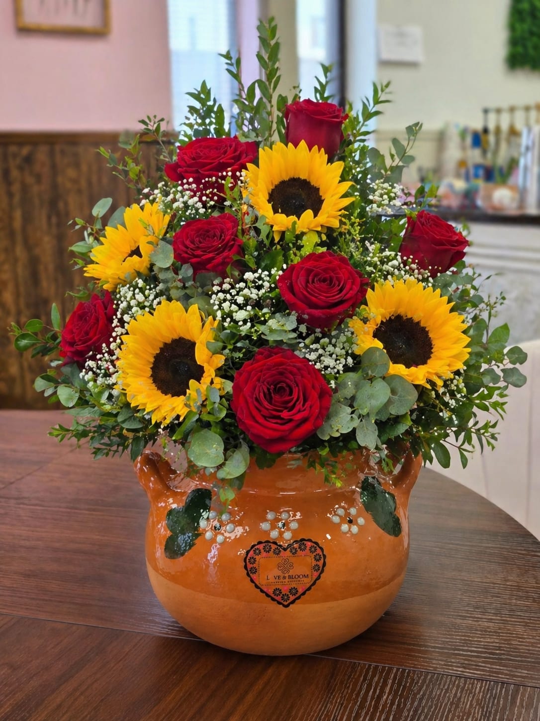 La Rosita Ollita - Sunflower &amp; Rose Ollita Arrangement ️  Bright, bold, and full of love—this stunning arrangement features vibrant sunflowers and classic red roses beautifully designed with fresh greenery and delicate accents, all arranged in a traditional handcrafted Ollita clay pot. The combination of sunny yellows and rich reds creates the perfect balance of warmth, joy, and elegance.  This arrangement is perfect for Mother’s Day, birthdays, anniversaries, or simply to brighten someone’s day. The keepsake Ollita pot adds a meaningful, cultural touch that can be enjoyed long after the flowers. Please note: Flower placement and exact blooms may vary slightly based on freshness and availability, but the overall look and feel will remain just as beautiful. Available for local delivery, pickup, or walk-in orders in Dodge City and surrounding areas.                 sunflower rose arrangement Dodge City, Mother’s Day flowers Dodge City KS, red roses and sunflowers bouquet, florist Dodge City Kansas, flower delivery Dodge City KS, same day flower delivery Dodge City, Ollita flower arrangement, clay pot flower arrangement, rustic floral arrangement Dodge City, send flowers to mom Dodge City, birthday flowers Dodge City KS, anniversary flowers Dodge City, local florist near me Dodge City, fresh flower arrangements Dodge City, pickup flowers Dodge City, walk-in florist Dodge City, flower shop near me Dodge City KS