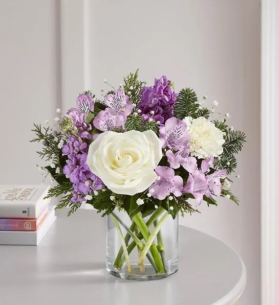 White rose and purple flower bouquet in a clear glass vase