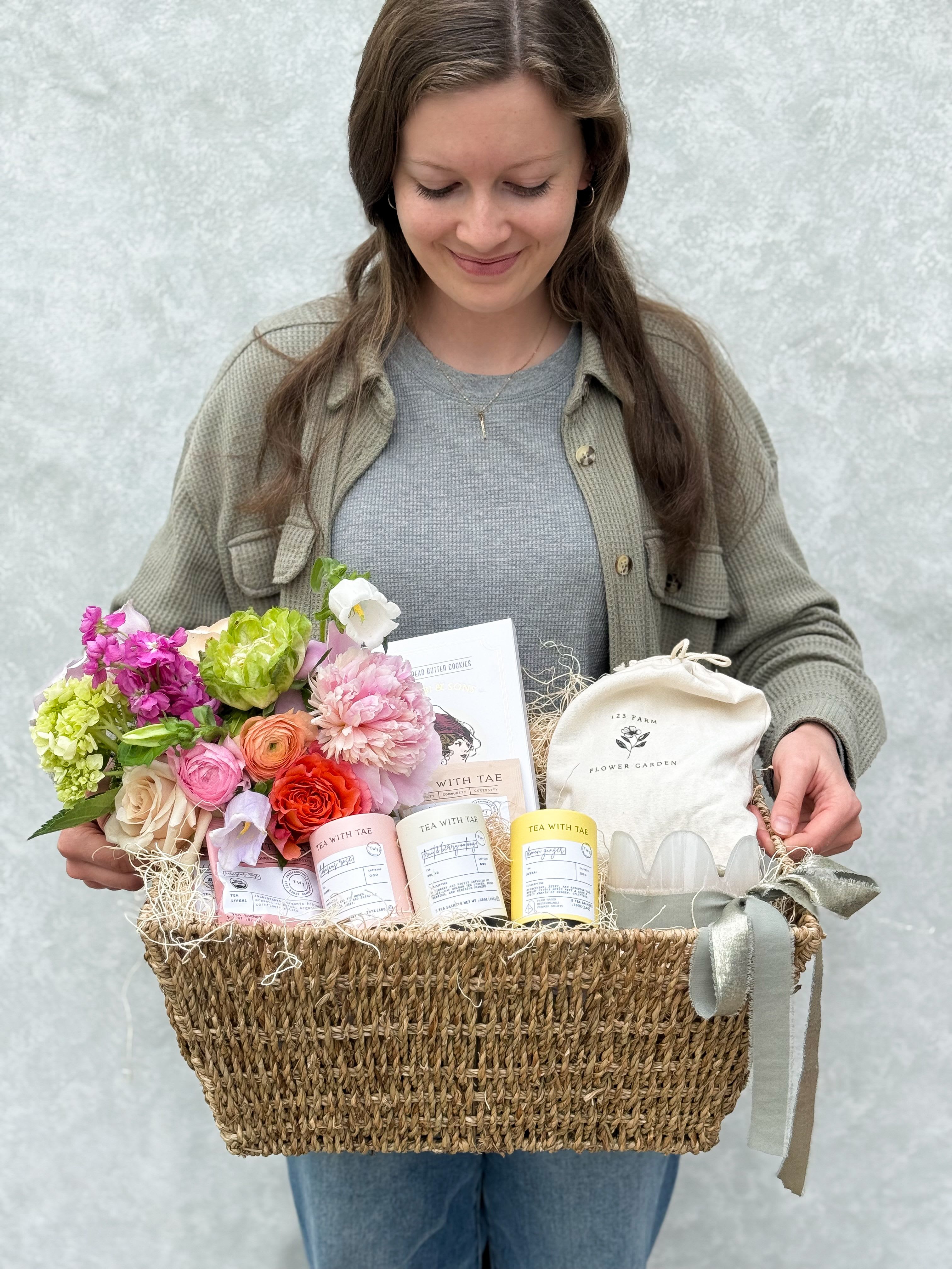 Made for Mom: Spring Gift Basket - This beautifully arranged basket pairs a fresh spring floral arrangement with a cozy collection of comforts...soothing teas, buttery shortbread cookies, a relaxing puzzle, and a softly glowing soy candle. The perfect gift for Mother's Day.  