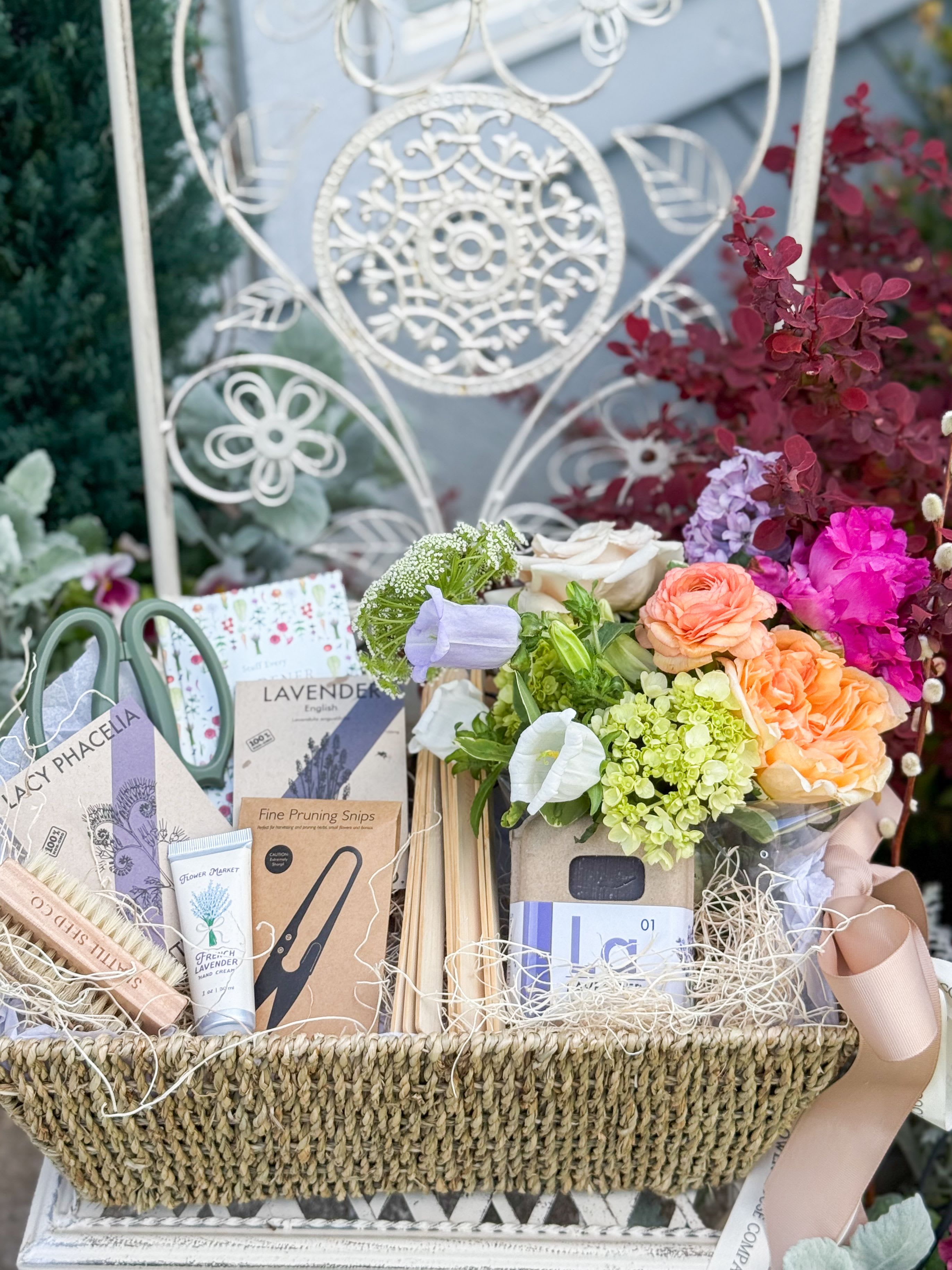 For the Gardener Basket - A thoughtful blend of beauty, tools, and self-care for anyone who loves to grow. This curated basket includes a fresh seasonal floral arrangement, fine pruning snips, a pair of garden shears, wooden plant labels, and two flower seed packets to inspire new blooms. For comfort after time in the garden, it features lavender soap, nourishing hand cream, and a gardener’s nail brush. A copy of Stuff Every Gardener Should Know completes this practical and inspiring collection. Perfectly arranged in a ready-to-gift basket, it’s a meaningful way to celebrate every gardener’s passion.