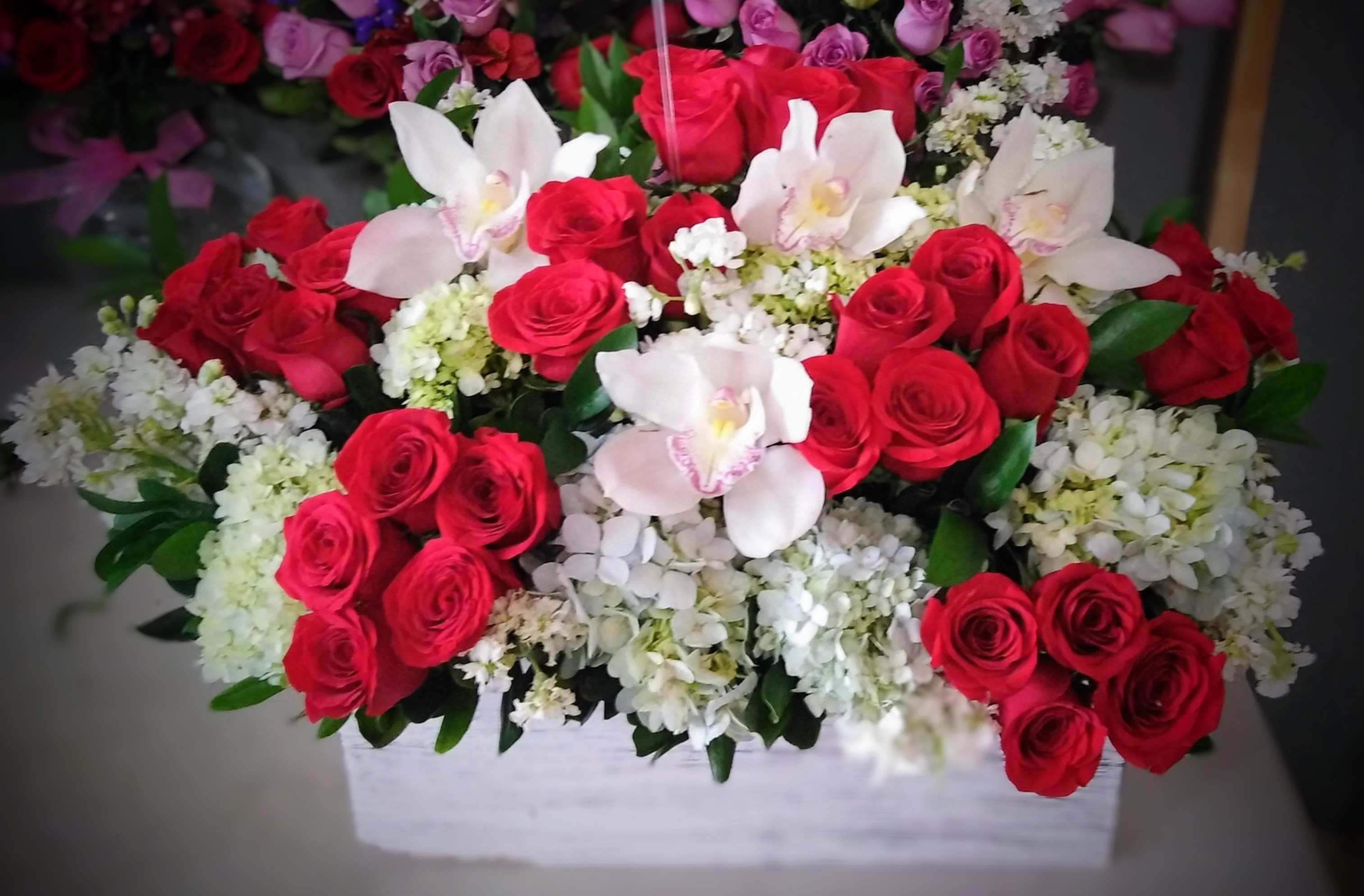 Luxury Roses &amp; Orchids Arrangement - A breathtaking luxury flower arrangement in San Antonio featuring fresh red roses, white hydrangeas, elegant orchids, and premium seasonal blooms beautifully designed in a modern wooden container. Handcrafted by Snyder Flowers San Antonio, this romantic floral arrangement combines timeless beauty and sophistication, making it perfect for anniversaries, Valentine’s Day, birthdays, romantic surprises, weddings, or luxury gifts.   We proudly offer same-day flower delivery in San Antonio with fresh premium flowers and exceptional customer service.  Elegant floral designs created with high-quality roses, orchids, hydrangeas, and luxury garden-style arrangements.  Serving Stone Oak, Medical Center, Alamo Heights, Cibolo, Universal City, Live Oak, Helotes, Castle Hills, Shavano Park, and Downtown San Antonio.  Looking for a trusted florist in San Antonio, same day flower delivery, or luxury rose arrangements near you? Snyder Flowers creates handcrafted floral designs with fresh roses, orchids, and premium flowers delivered beautifully for every special occasion.