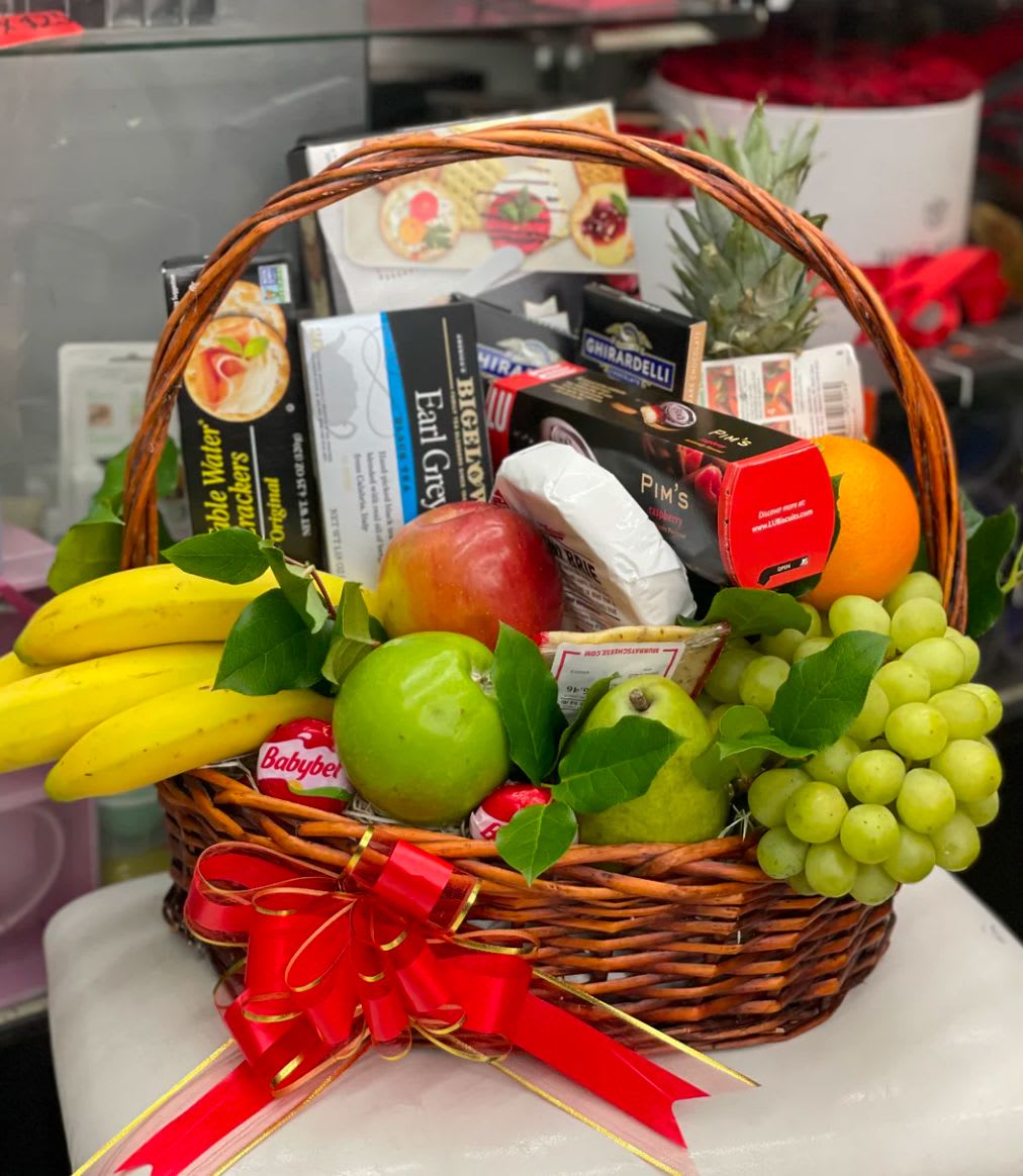 Gift basket with fruit and assorted snack boxes tied with a red ribbon