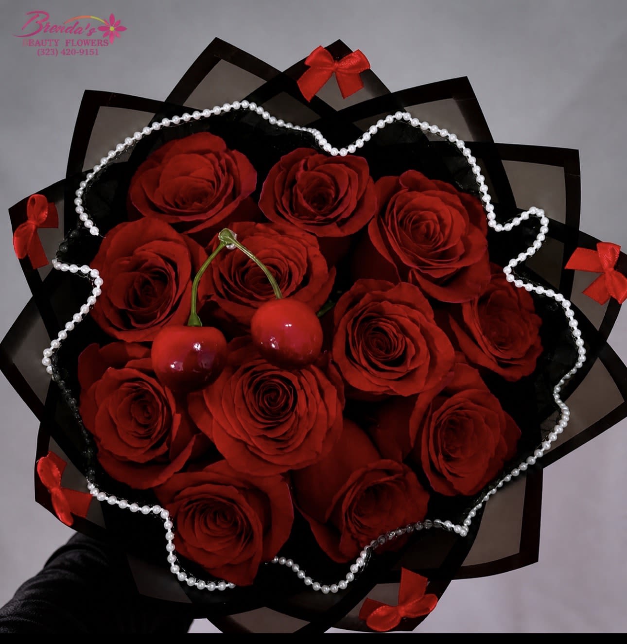 Bouquet of red roses wrapped in black paper with pearl trim and red bows