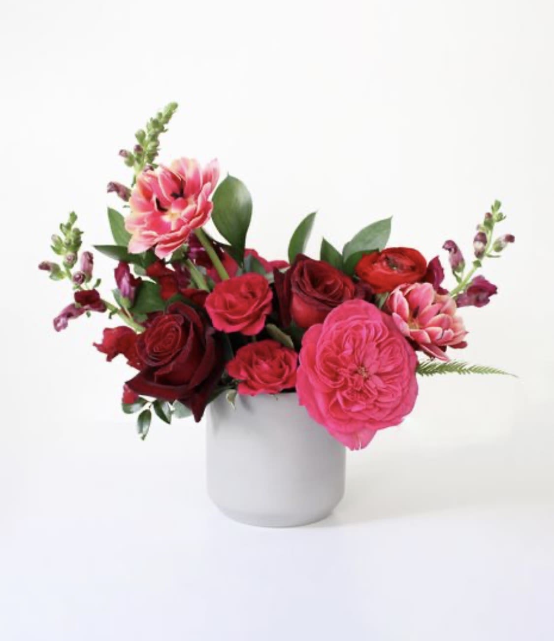 Pink and red roses arranged in a white vase