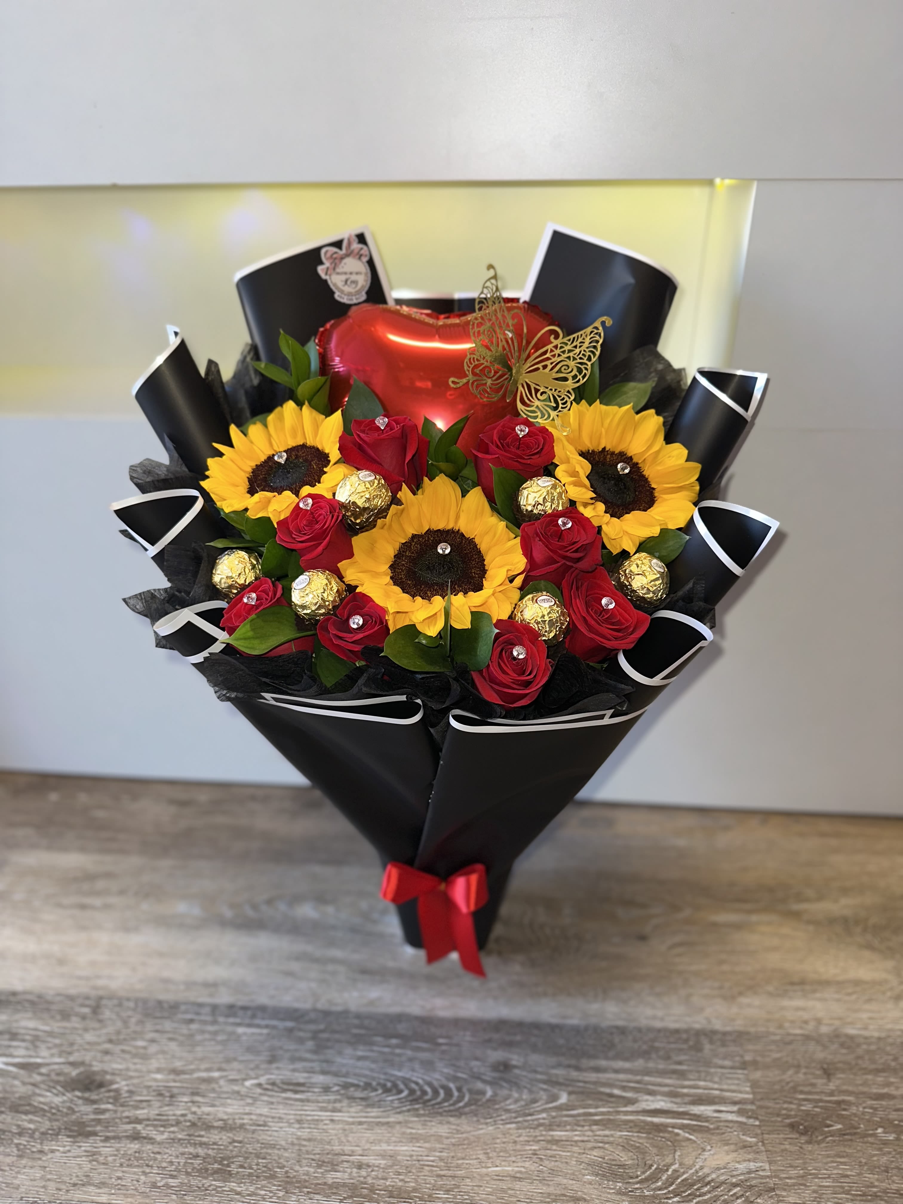 Bouquet of red roses and sunflowers with chocolates and a heart balloon